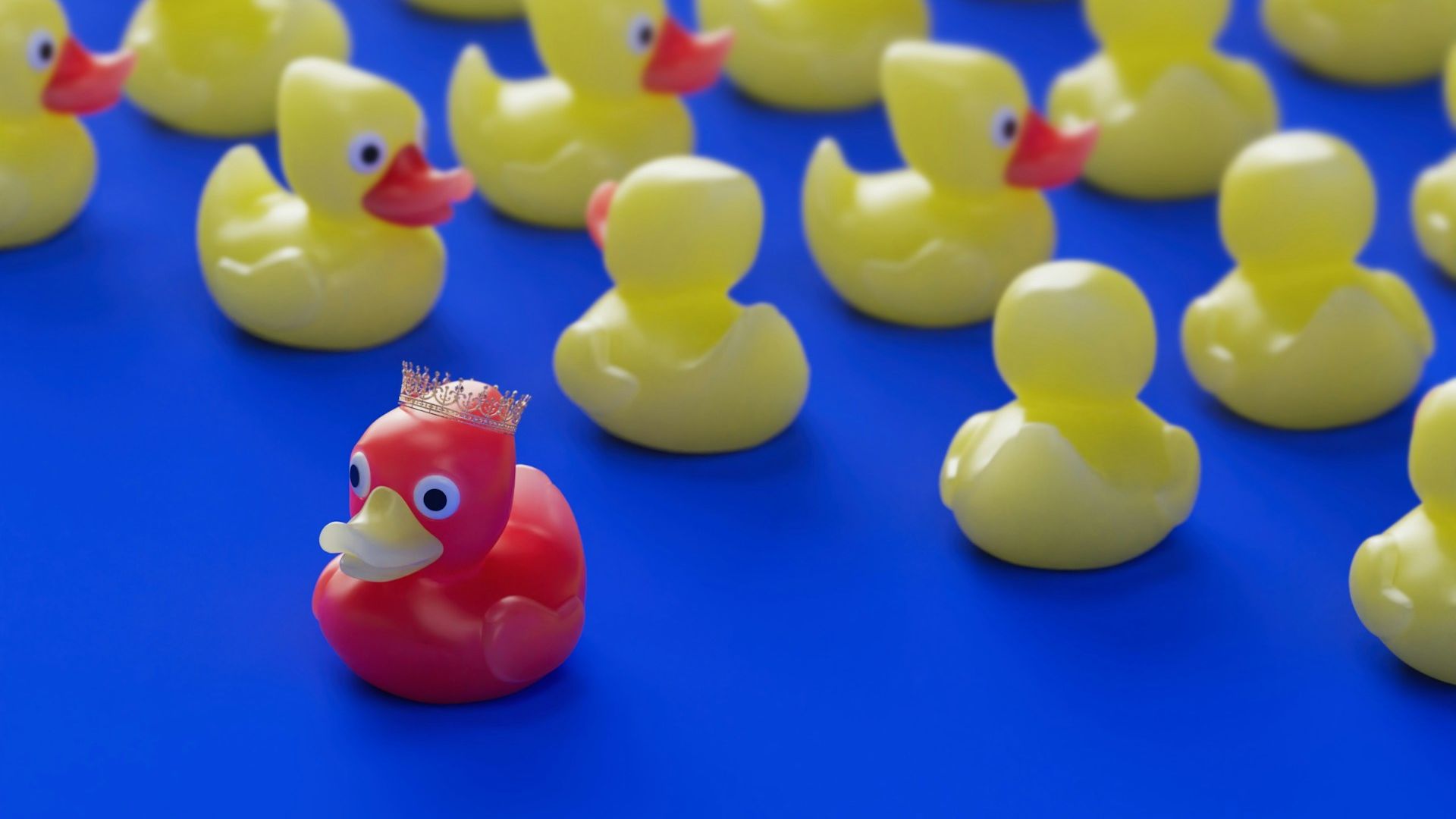 a red colored rubber duck facing the opposite direction from multiple yellow rubber ducks