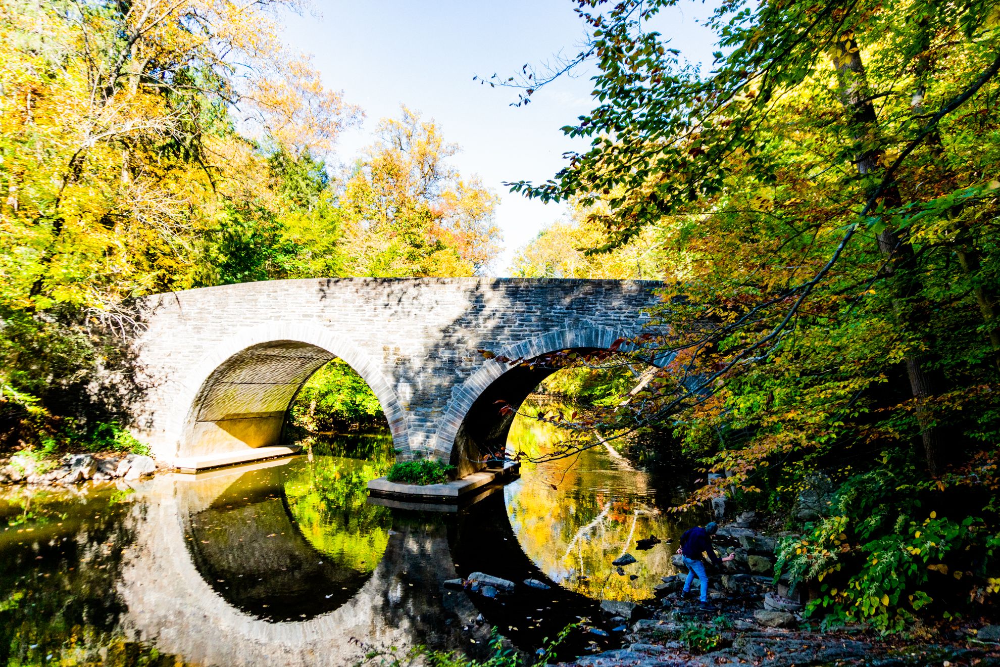 A man with his family skips a rock along the Wissahickon Creek in Wissahickon Valley Park in Philadelphia, PA