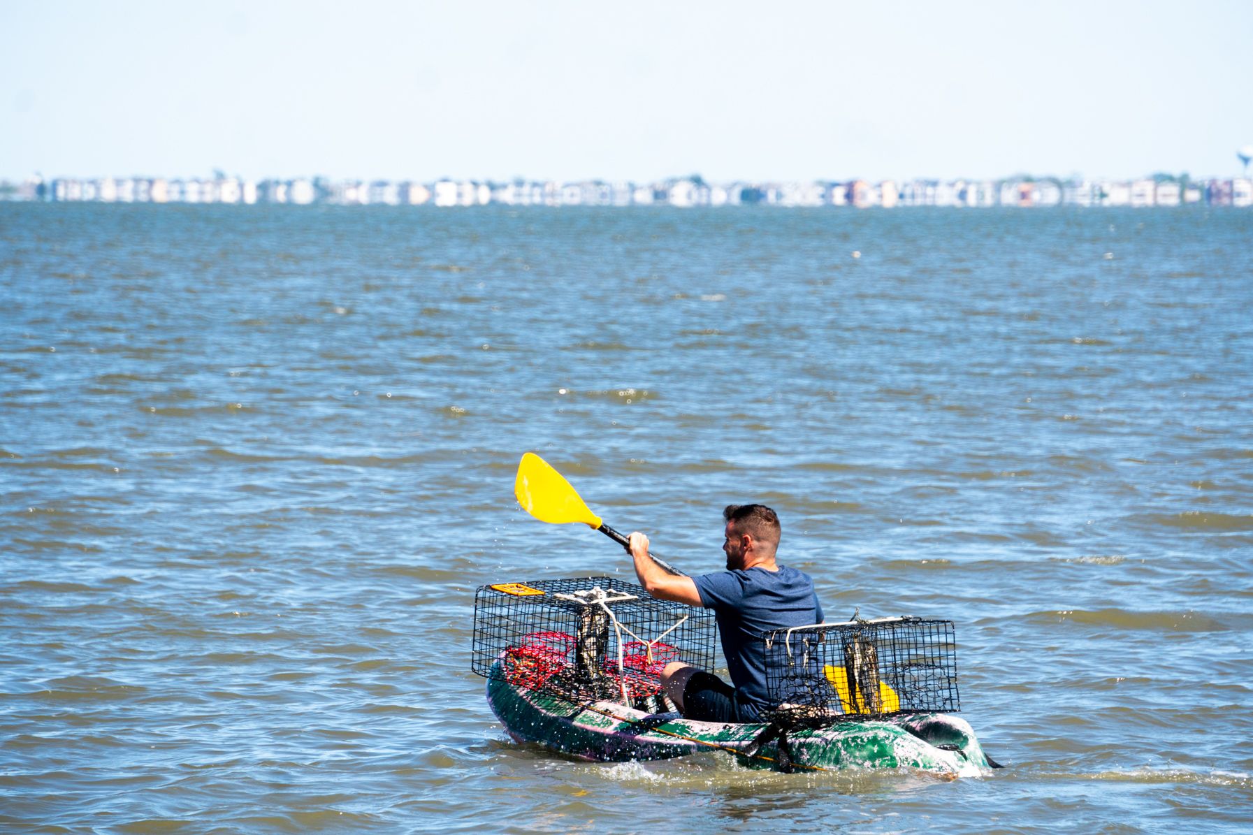 Paul paddling out with crab traps with Brigantine in the background