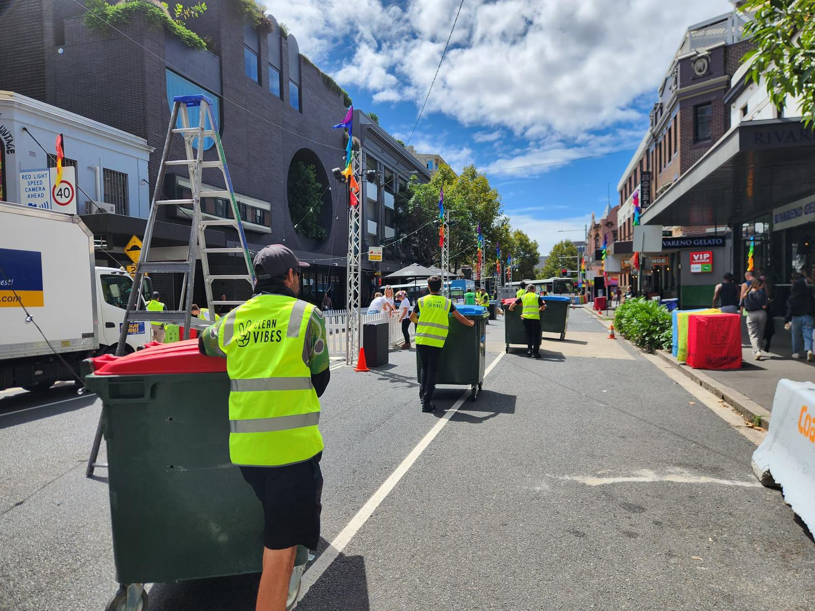 Clean Vibes cleaners with recycling bins walking down a street
