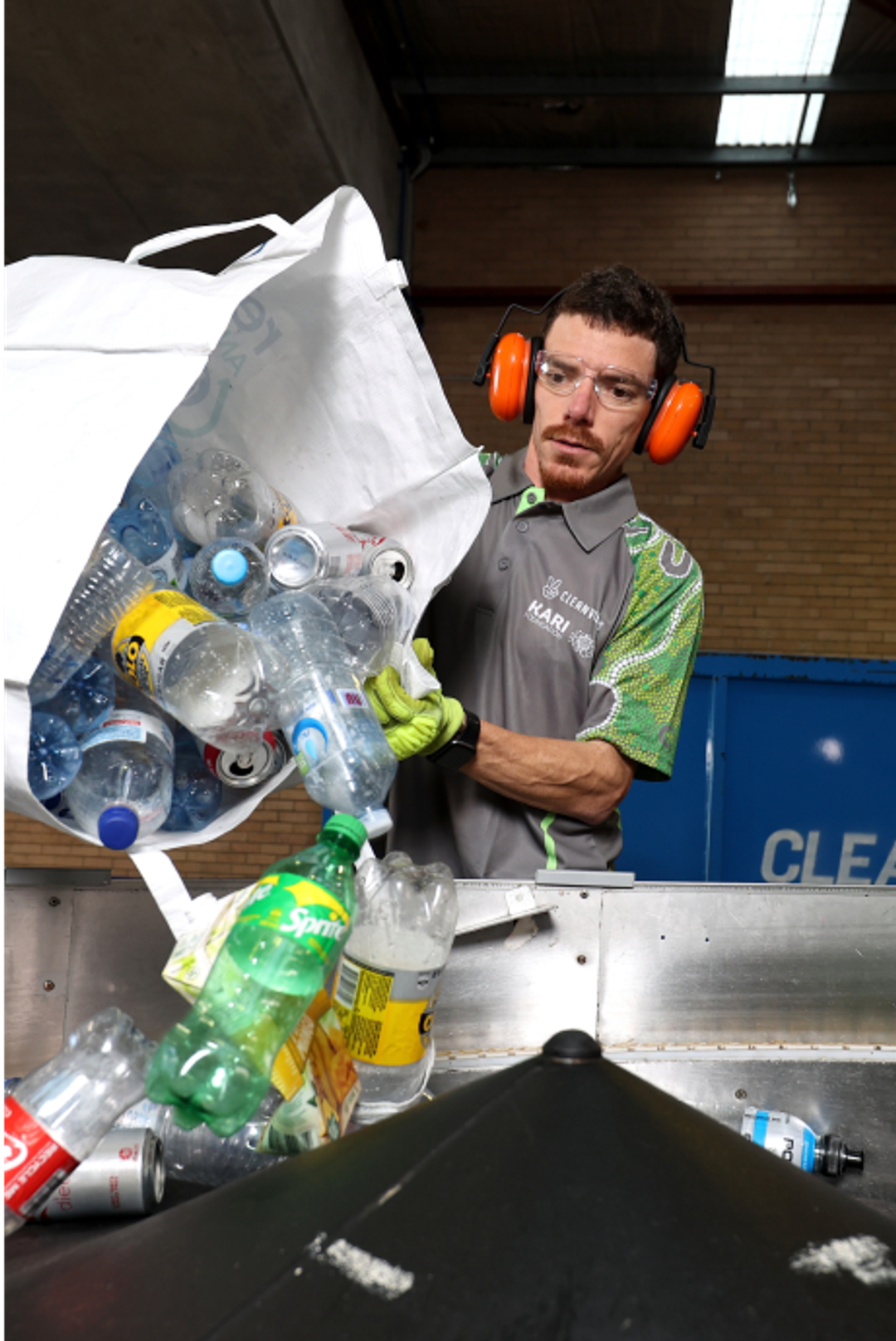 City Return and Earn employee emptying a bag or empty container in machine