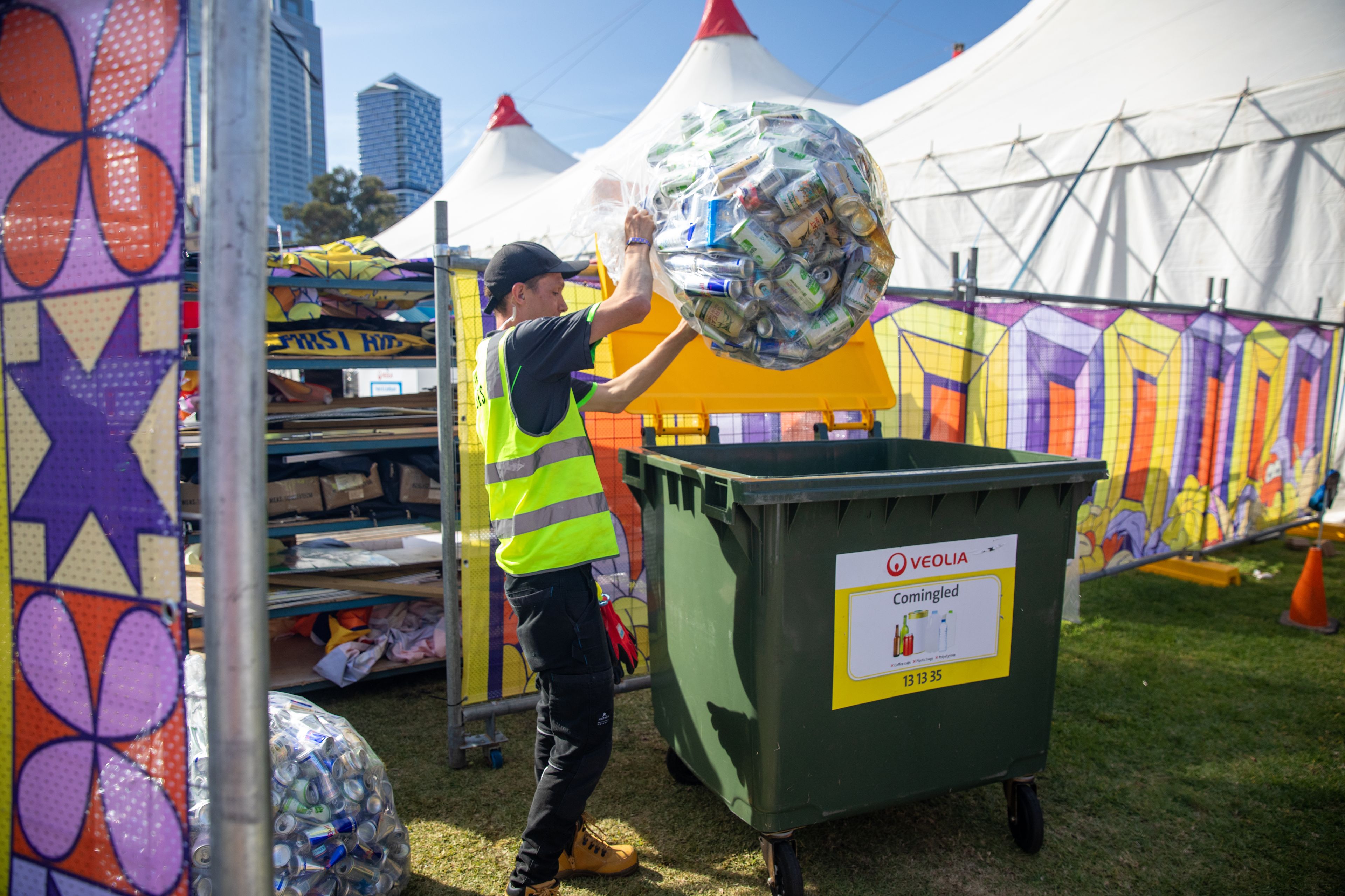 Clean Vibes staff throwing bag of empty aluminium cans in recycling bin