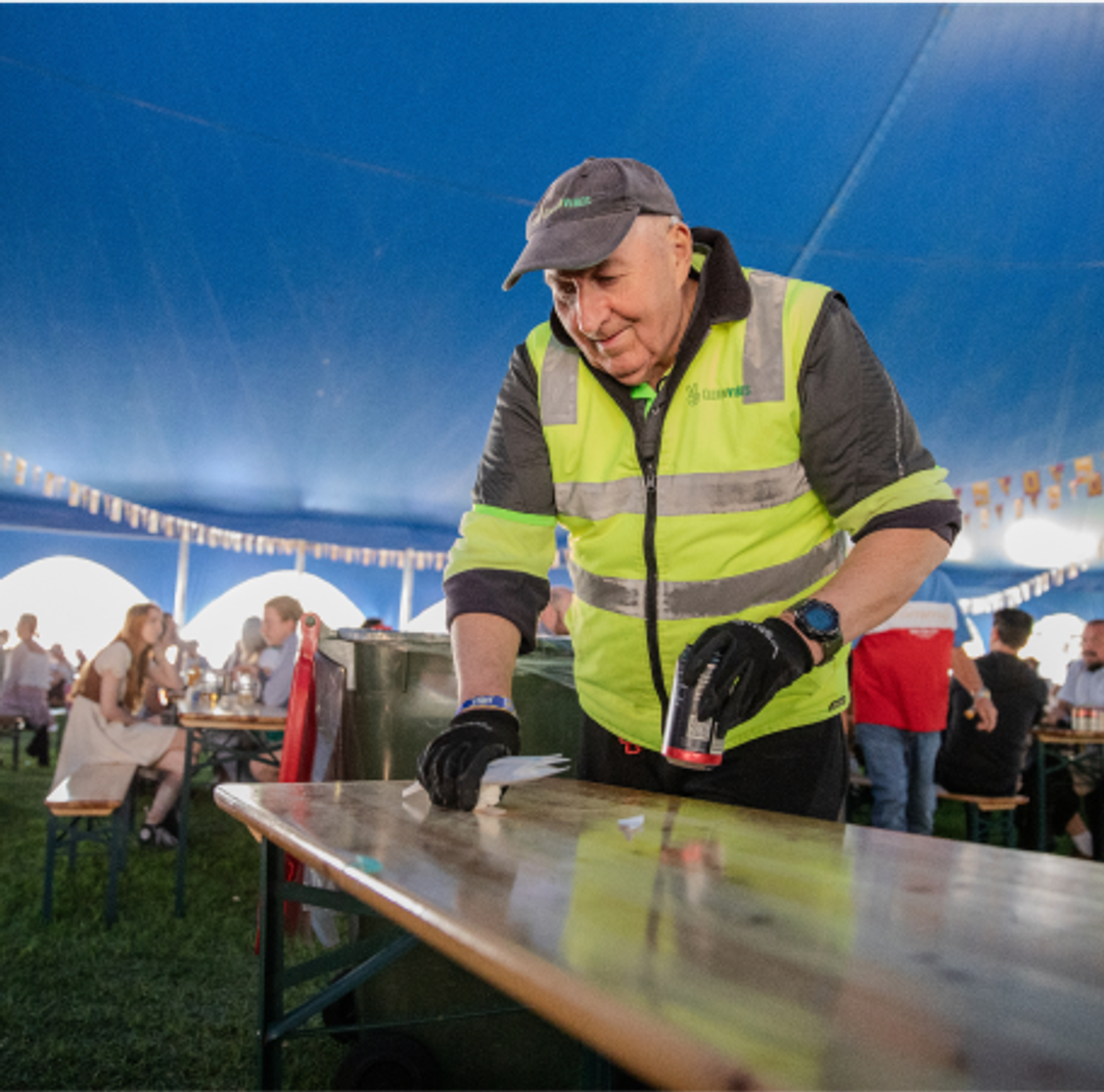 Clean Vibes employee cleaning table at a festival