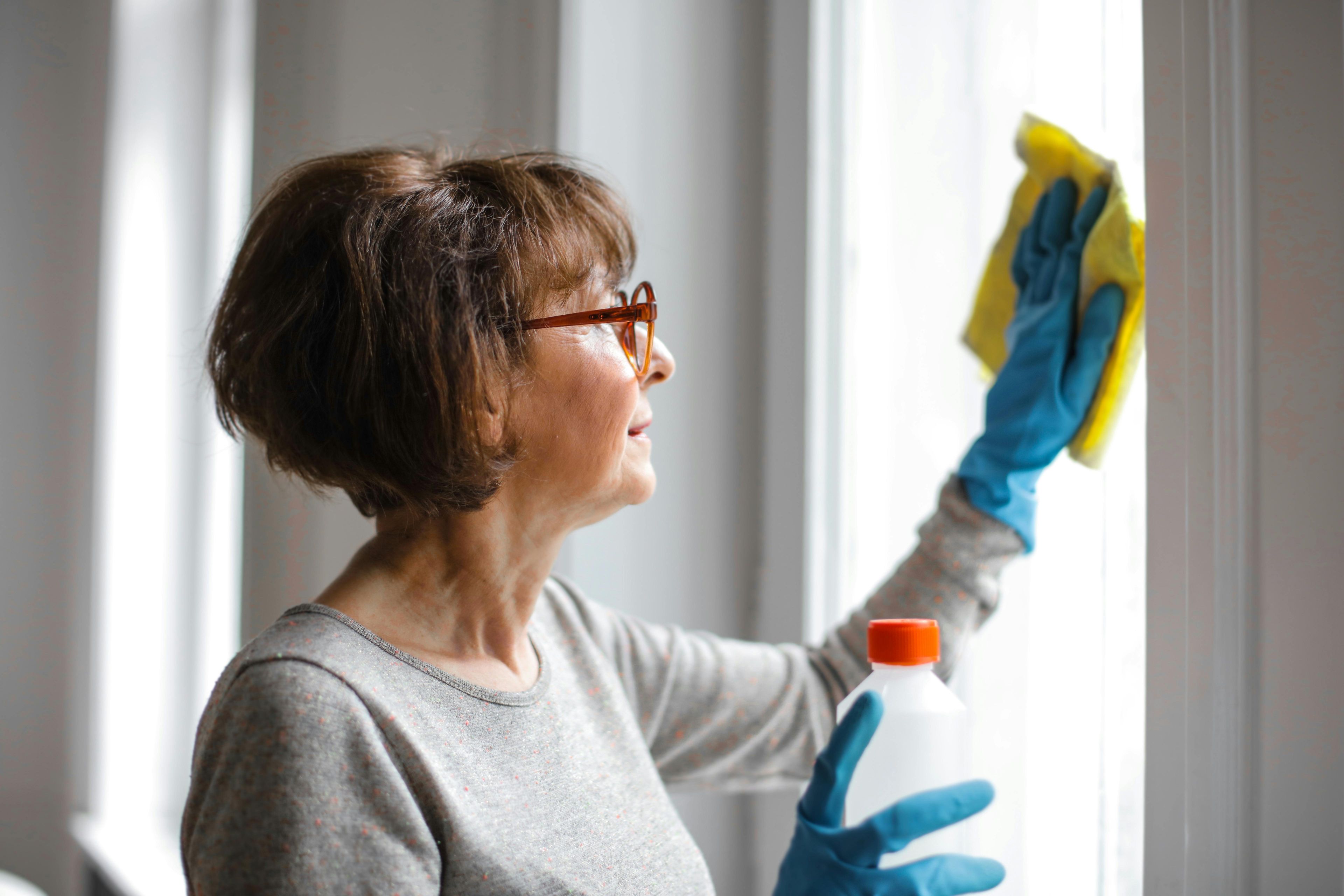 Woman wearing gloves disinfecting glass