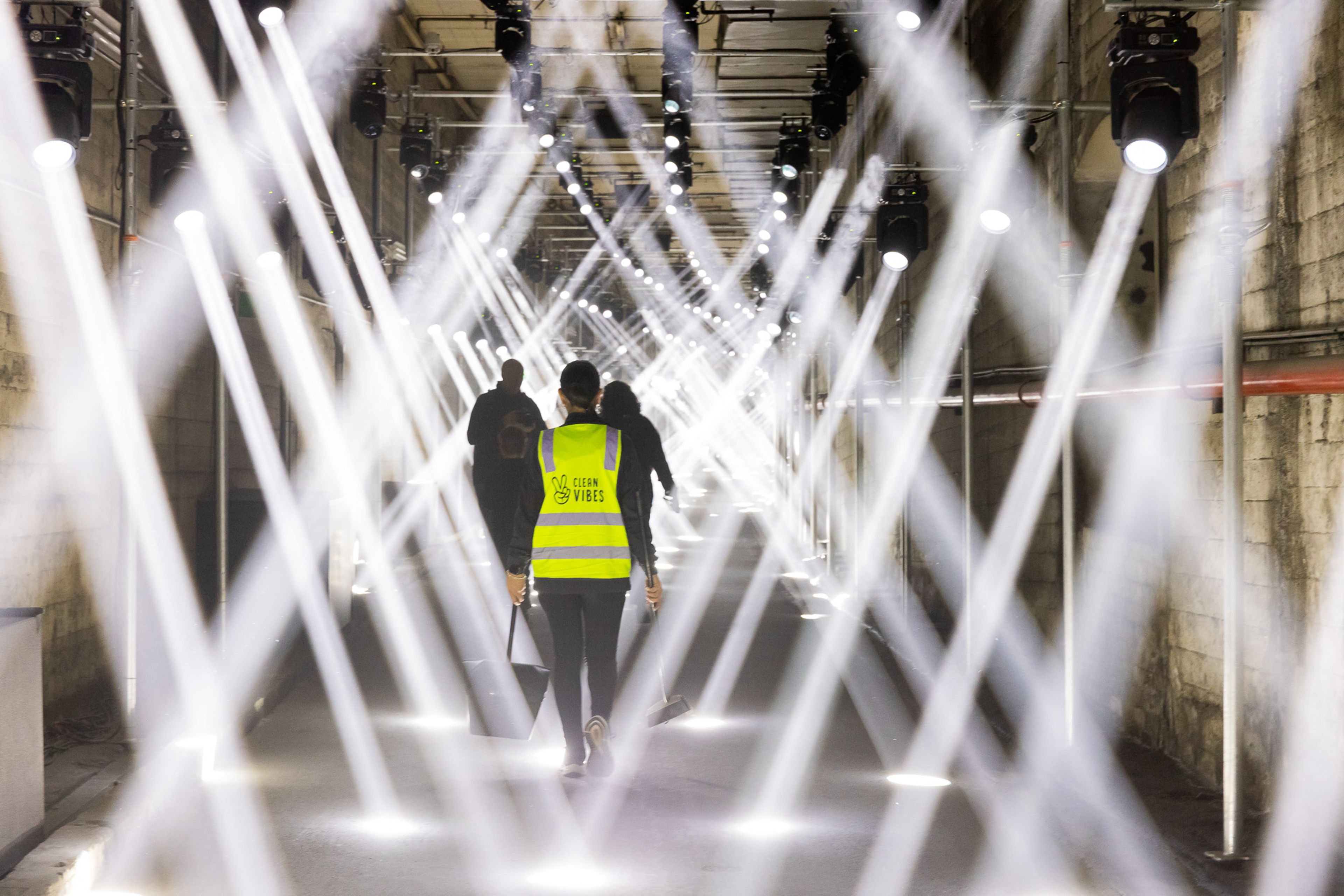 Clean Vibes staff walking under projectors at Sydney Vivid festival 2024