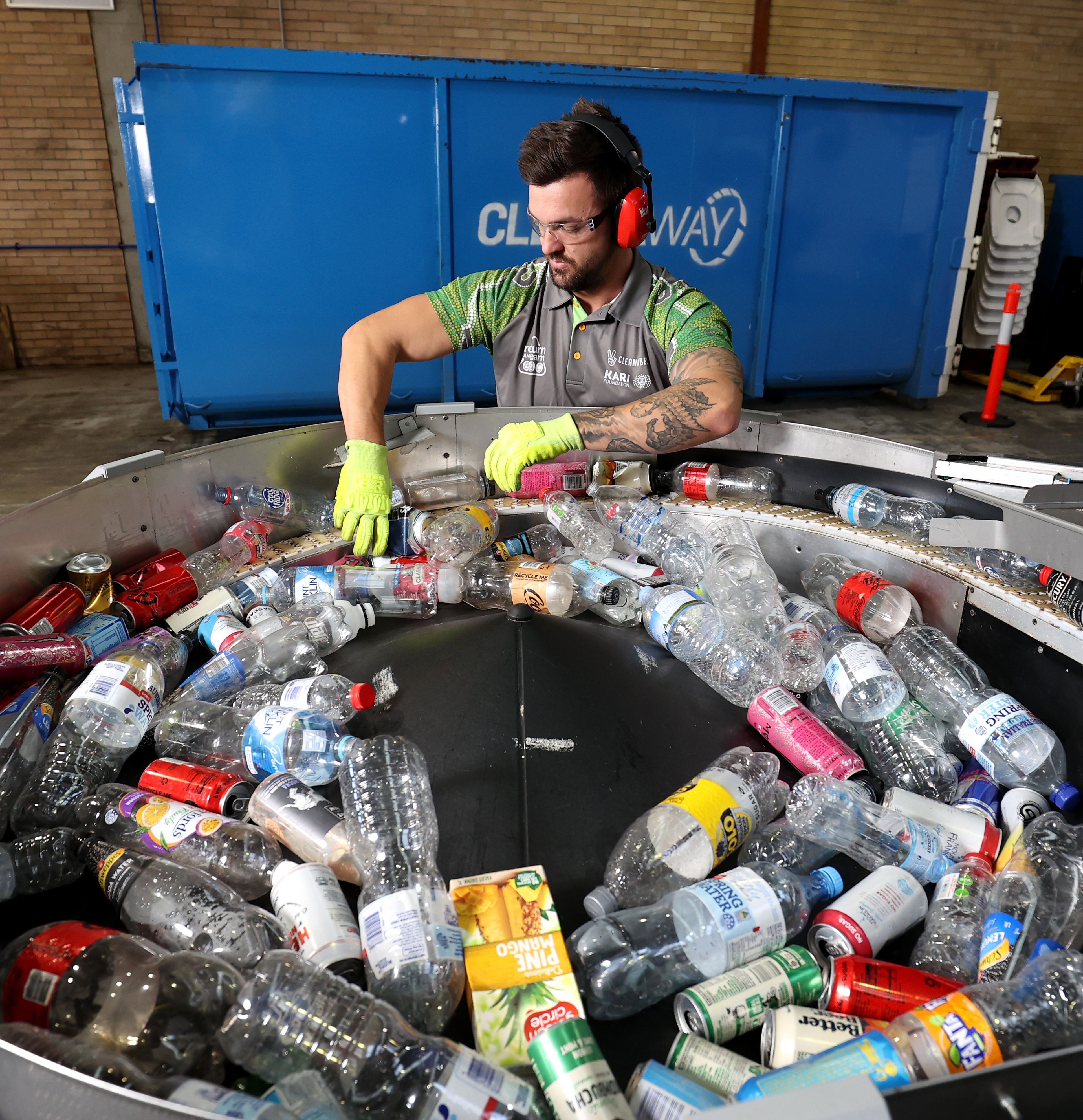 City Return and Earn staff recycling containers with a machine