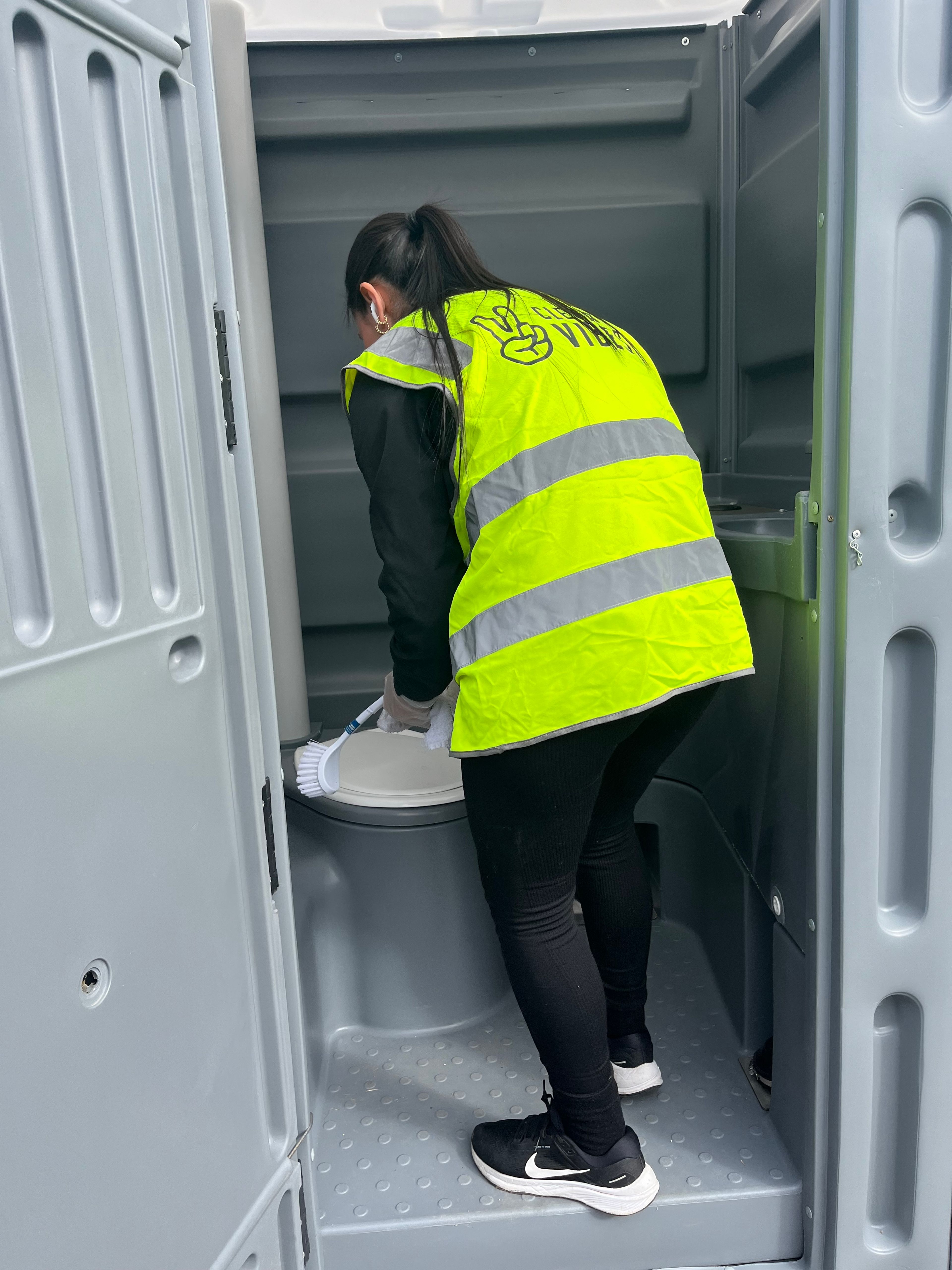 Clean Vibes staff cleaning toilet at music festival