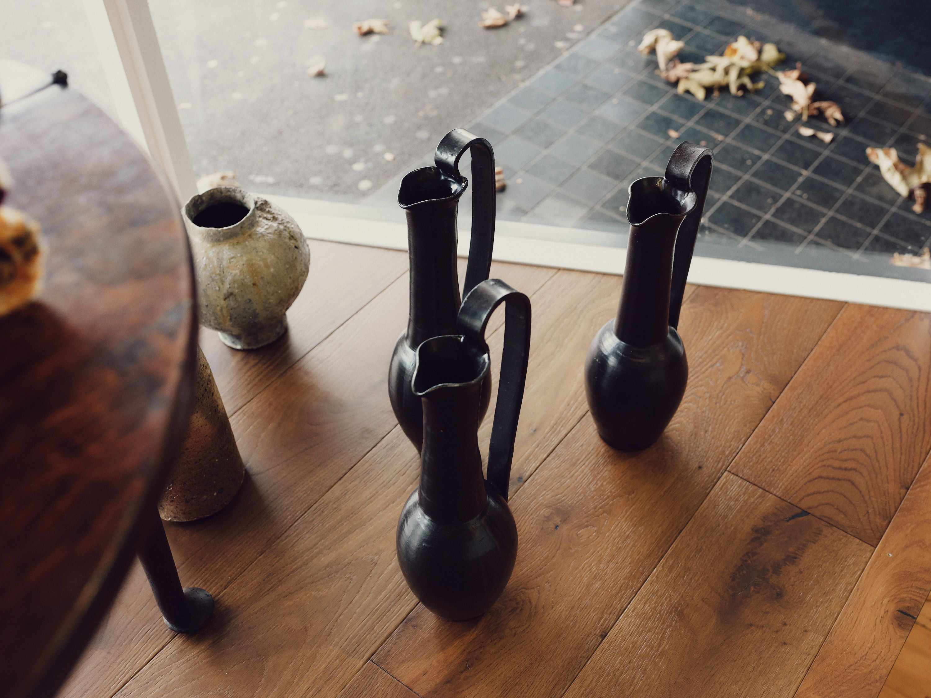 Three Etruscan inspired ceramic vases in a shop window display on a wooden floor