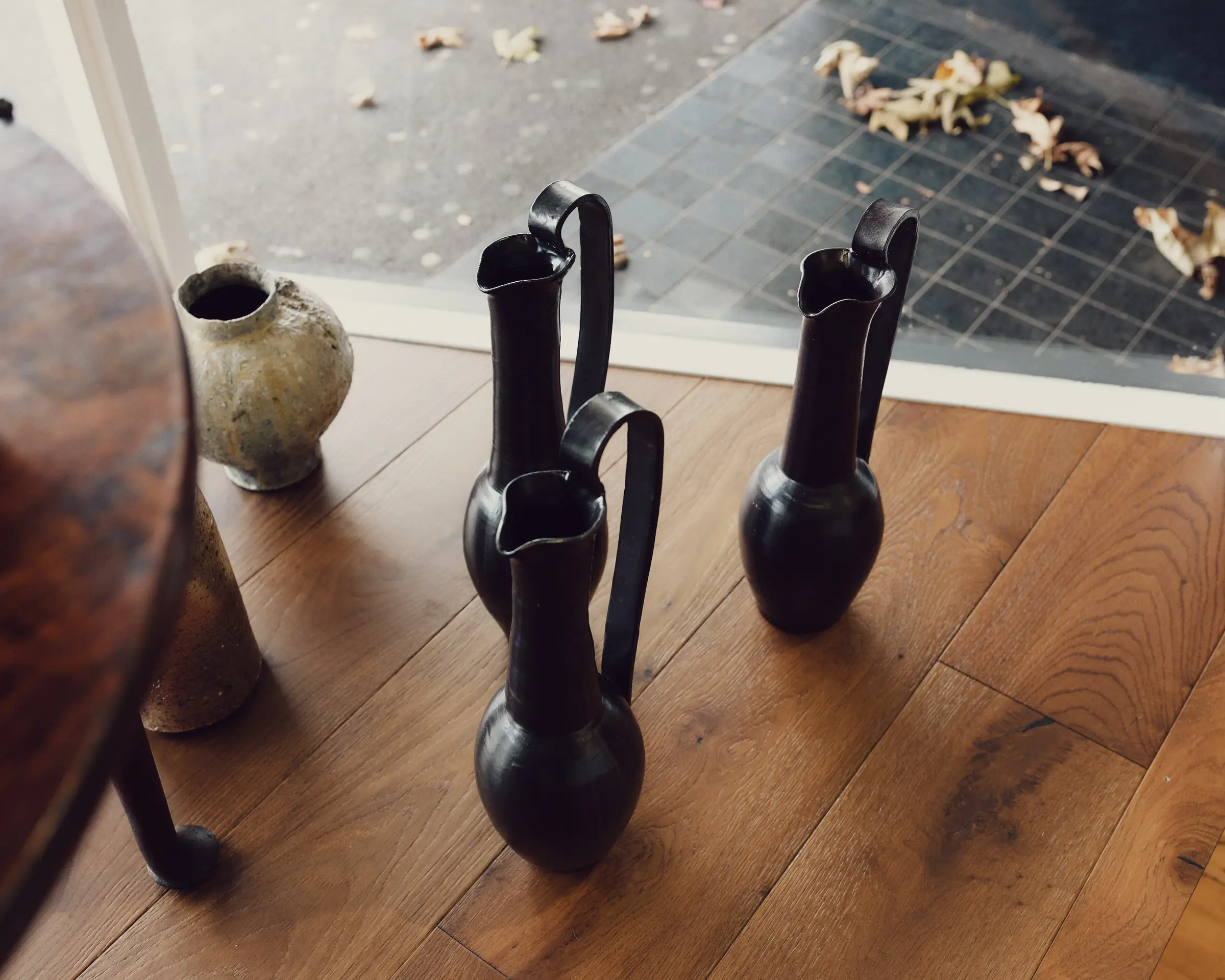 Three Etruscan inspired ceramic vases in a shop window display on a wooden floor