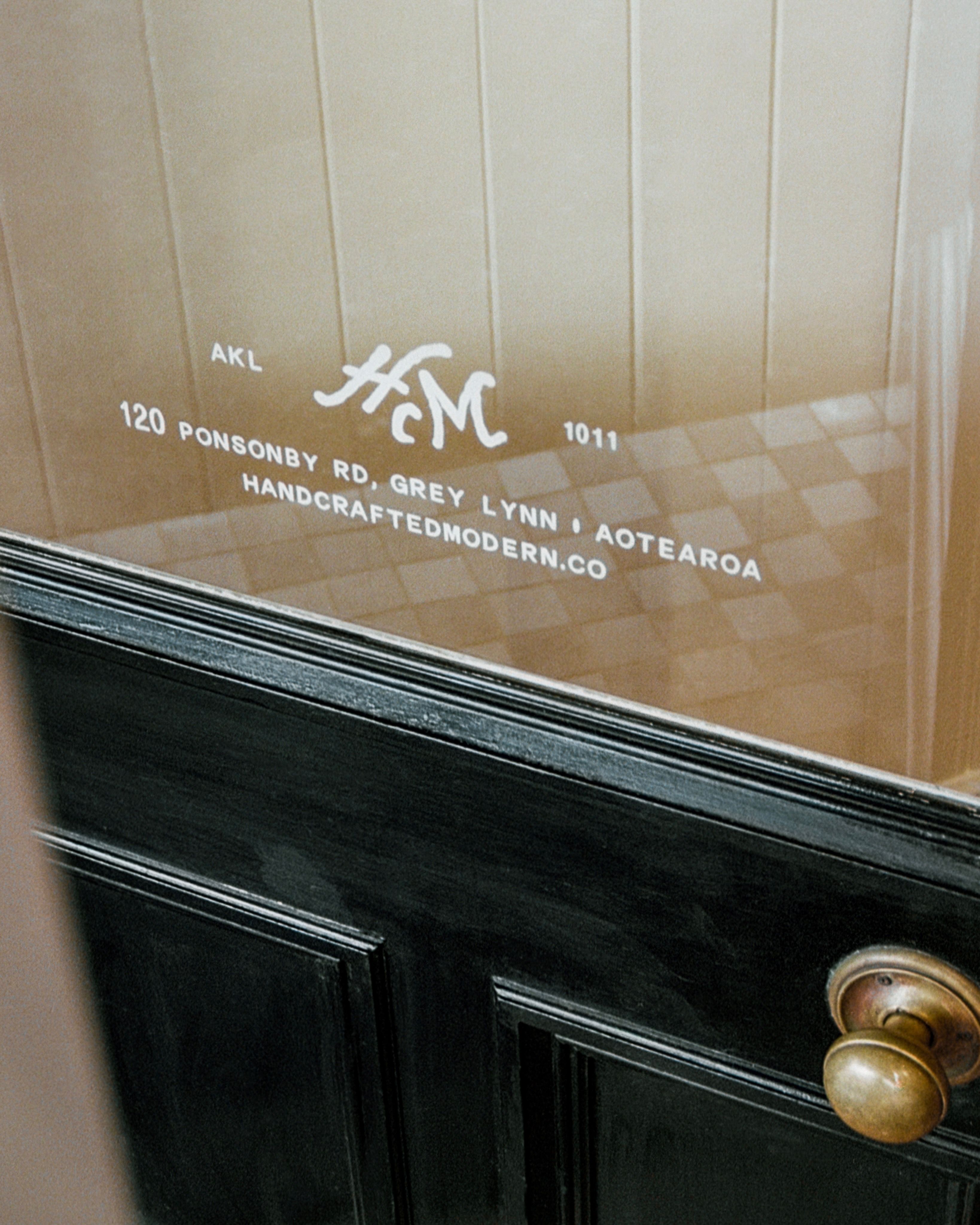 Hand-painted Handcrafted Modern monogram and entrance signage on the front door of our Ponsonby store in Auckland, Aotearoa New Zealand. 