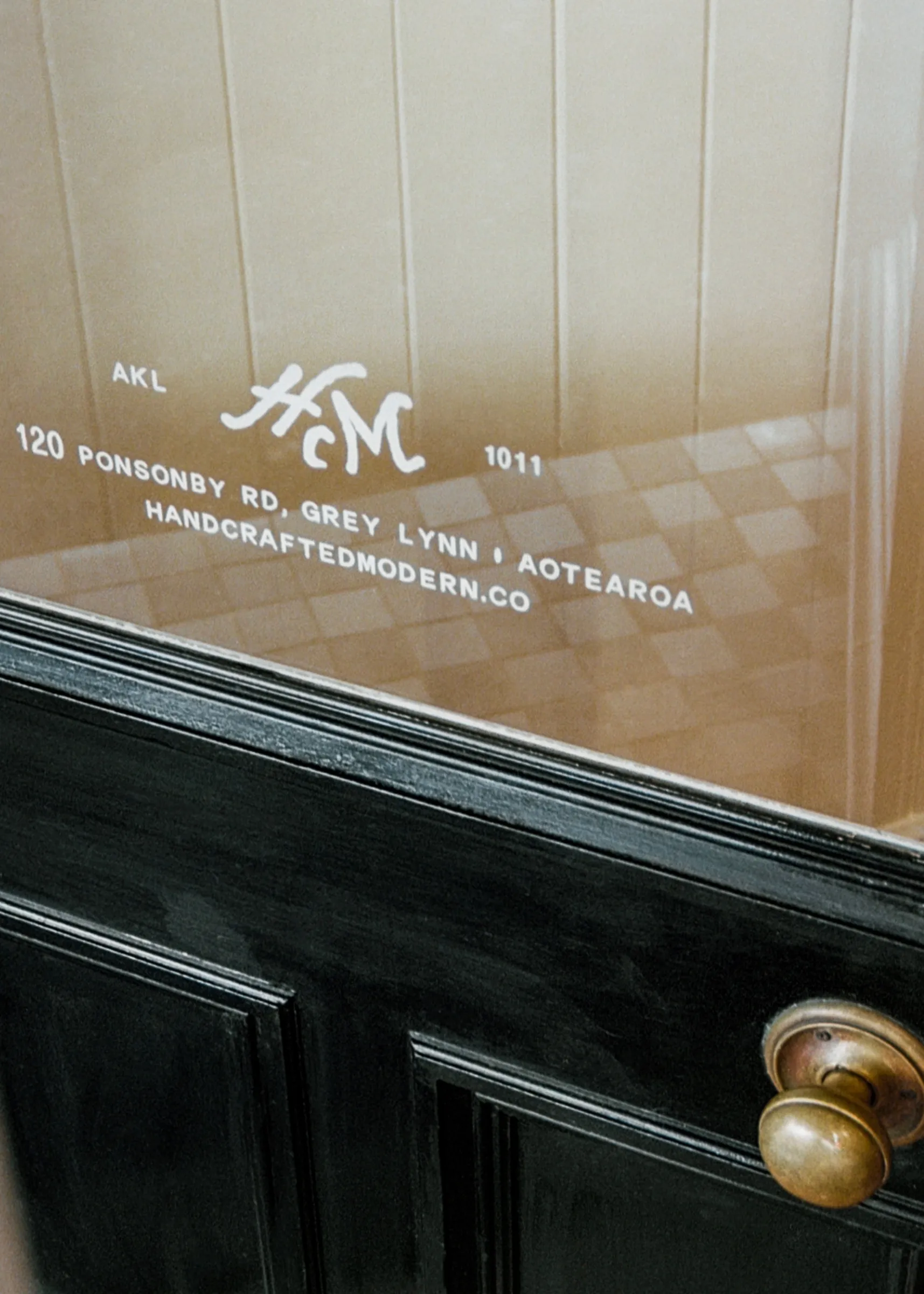 Hand-painted Handcrafted Modern monogram and entrance signage on the front door of our Ponsonby store in Auckland, Aotearoa New Zealand.