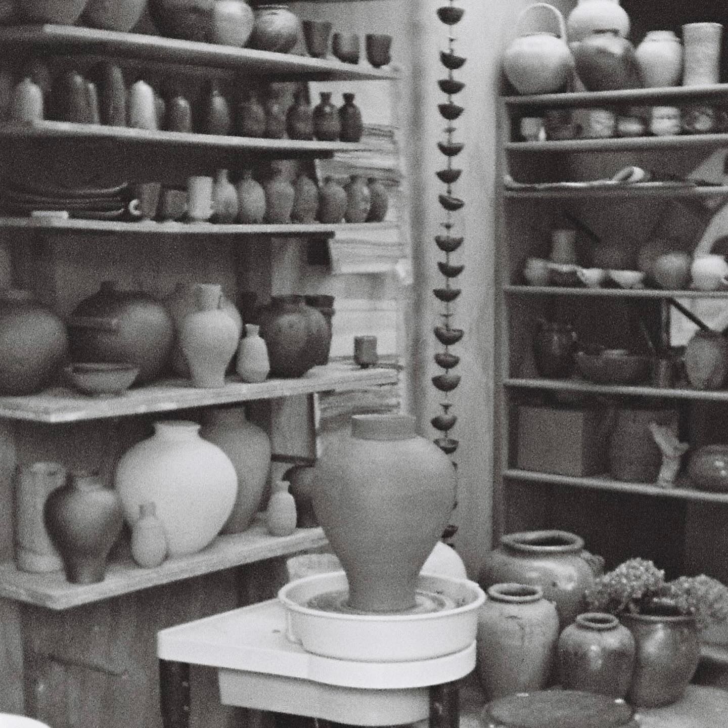 A black and white image of Holly Rose Morgans studio with ceramic vases and vessels lining the shelves 