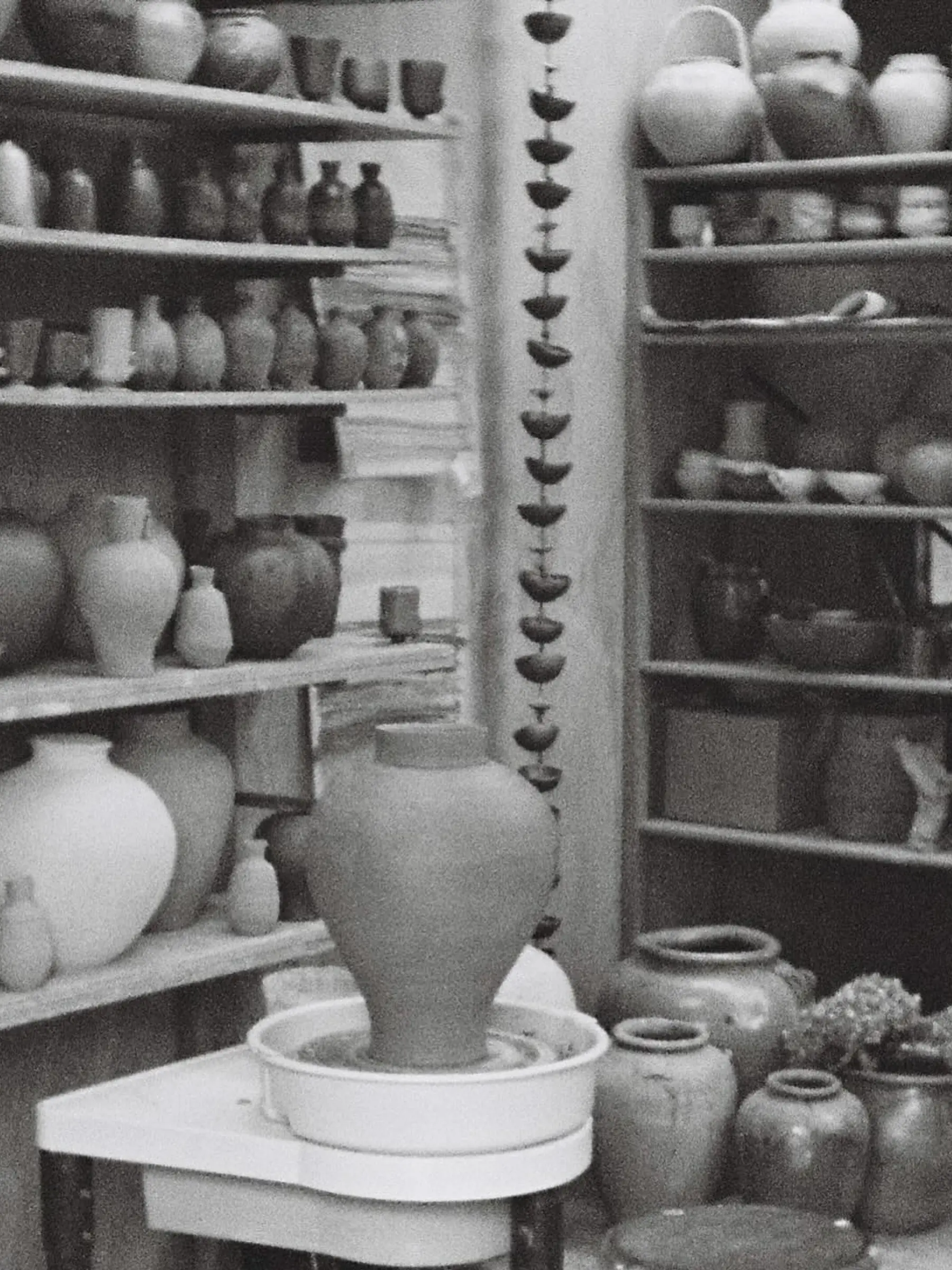A black and white image of Holly Rose Morgans studio with ceramic vases and vessels lining the shelves