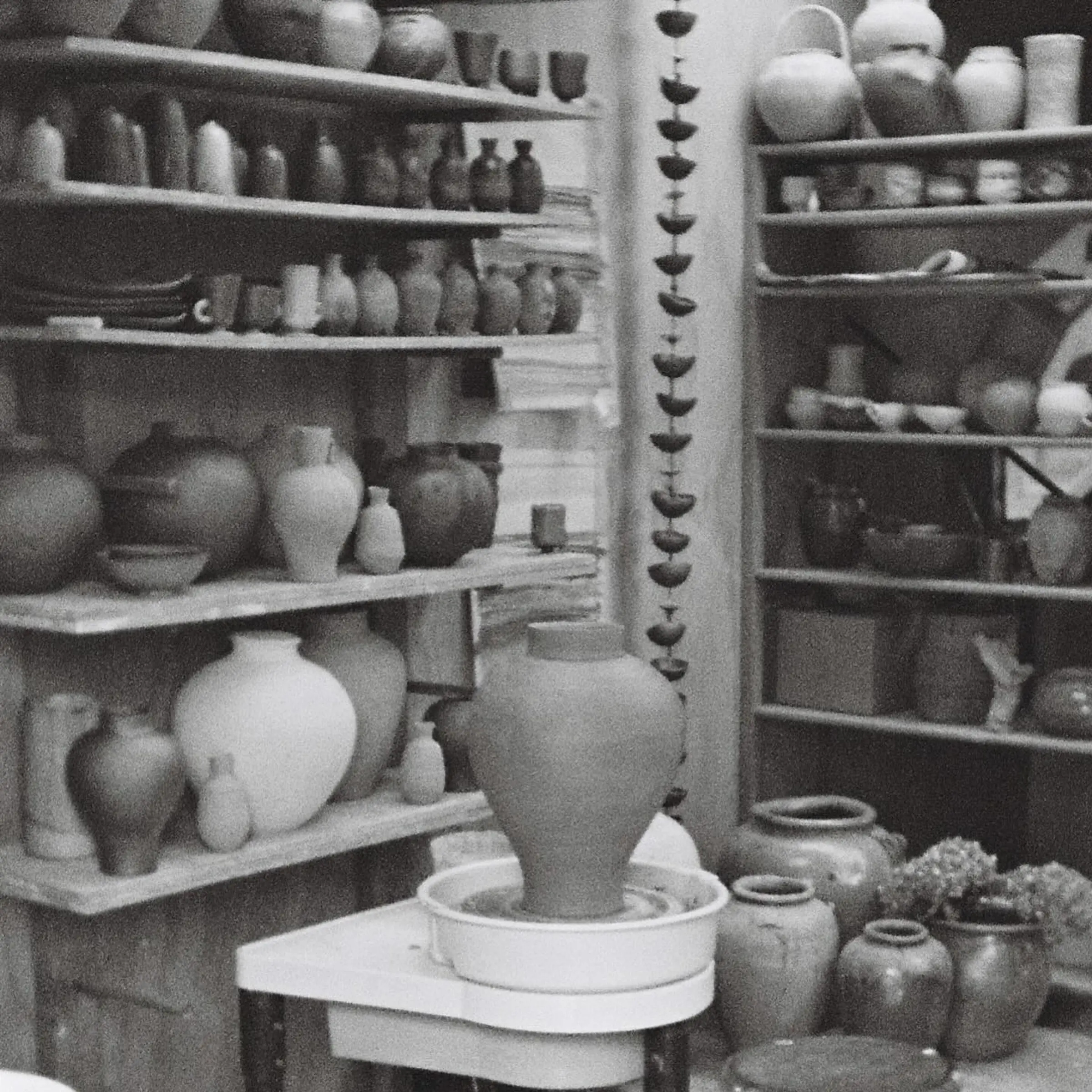 A black and white image of Holly Rose Morgans studio with ceramic vases and vessels lining the shelves