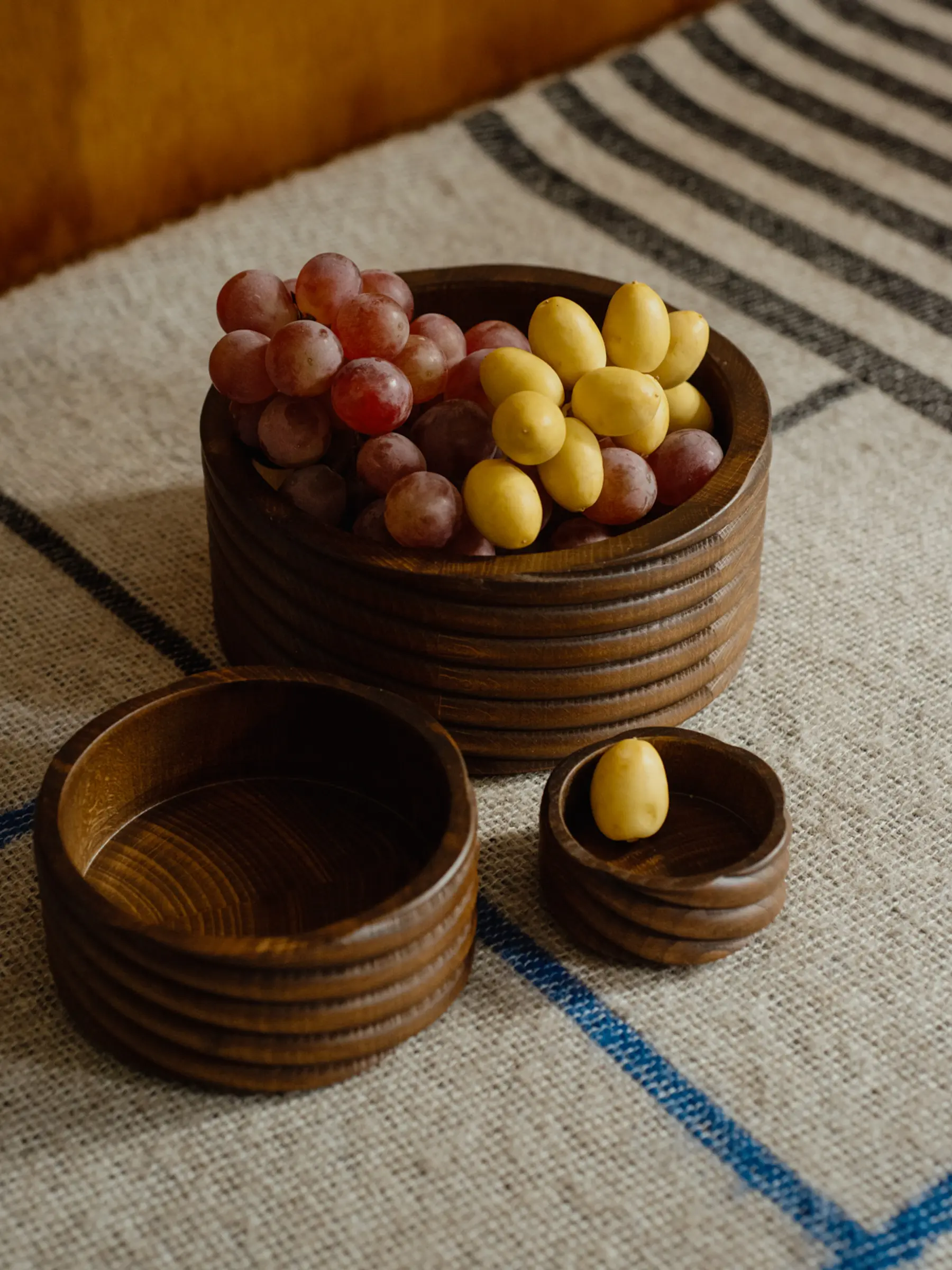 A collection of three Torsade hand turned bowls photographed on a woven blanket with a wooden background