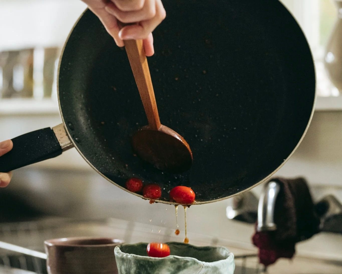 Courtney Petleys Round serving spoon hand carved from matai wood being used to pour tomatoes from a pan into a bowl