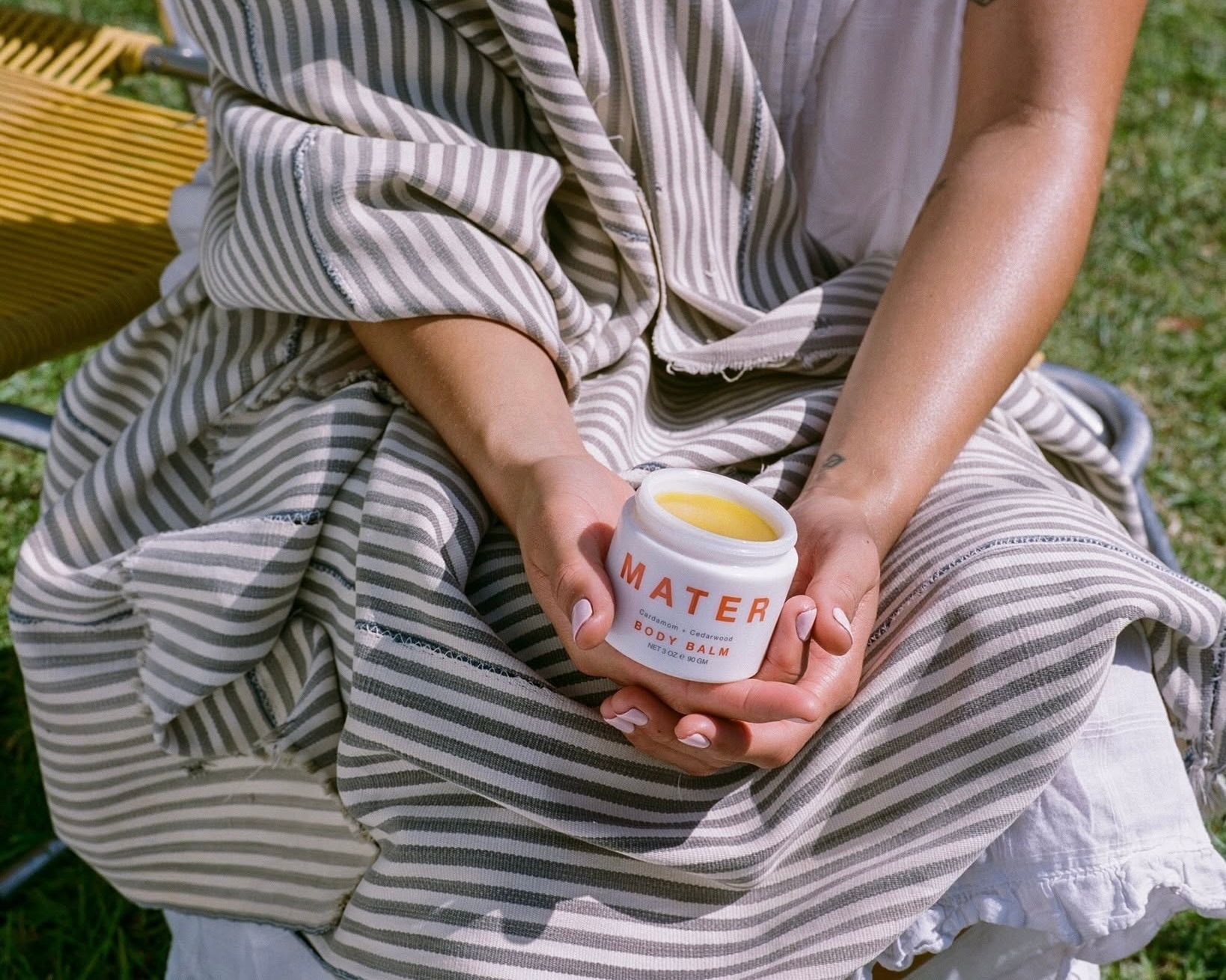 a woman holding the mater body balm glass jar