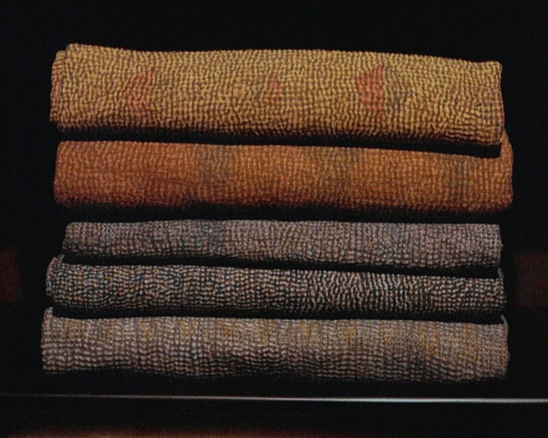 Stack of folded vintage cotton Kantha quilts in earthy tones, hand stitched from reclaimed cotton textiles and photographed on film.