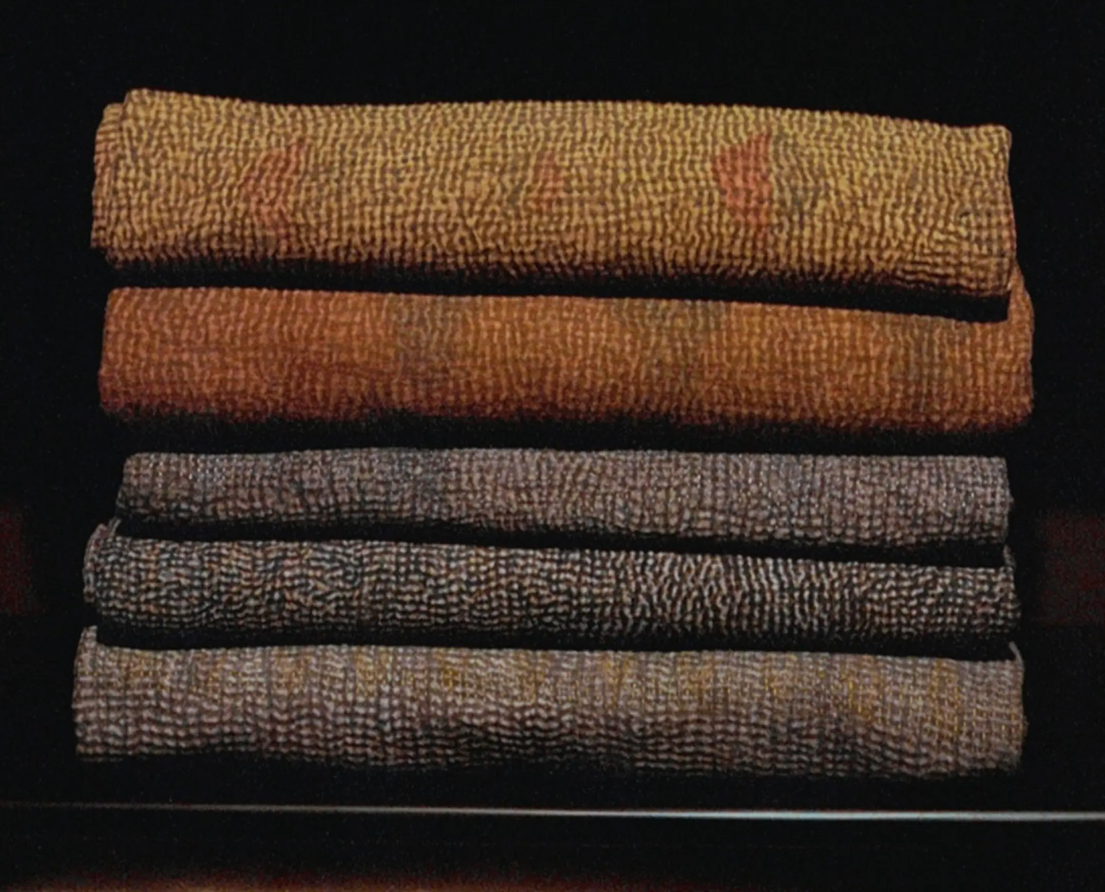 Stack of folded vintage cotton Kantha quilts in earthy tones, hand stitched from reclaimed cotton textiles and photographed on film.