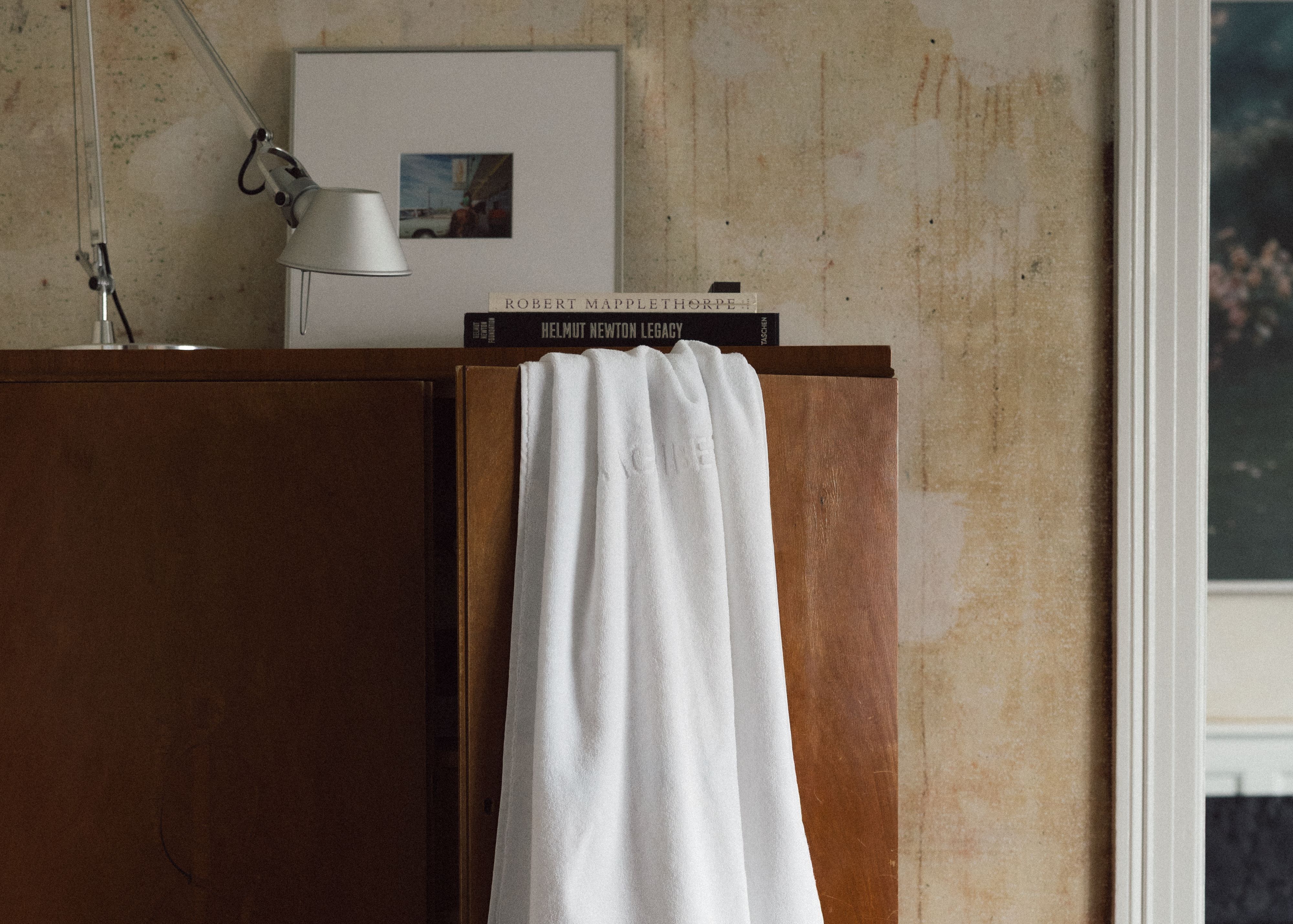 Magniberg gelato towel in white draped over a wooden cabinet styled in a home