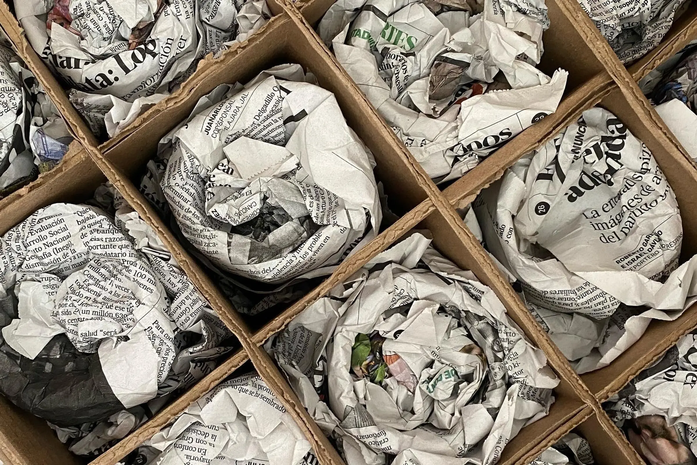 Cups wrapped in newspaper with cardboard separators ready to be shipped