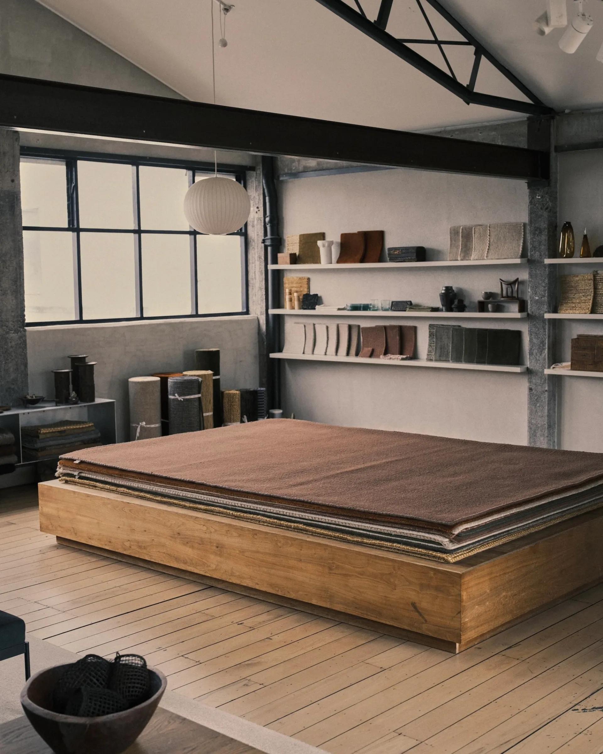 inside of Nodi's showroom with a stack of rugs and shelves with Handcrafted modern pieces and carpet swatches on them