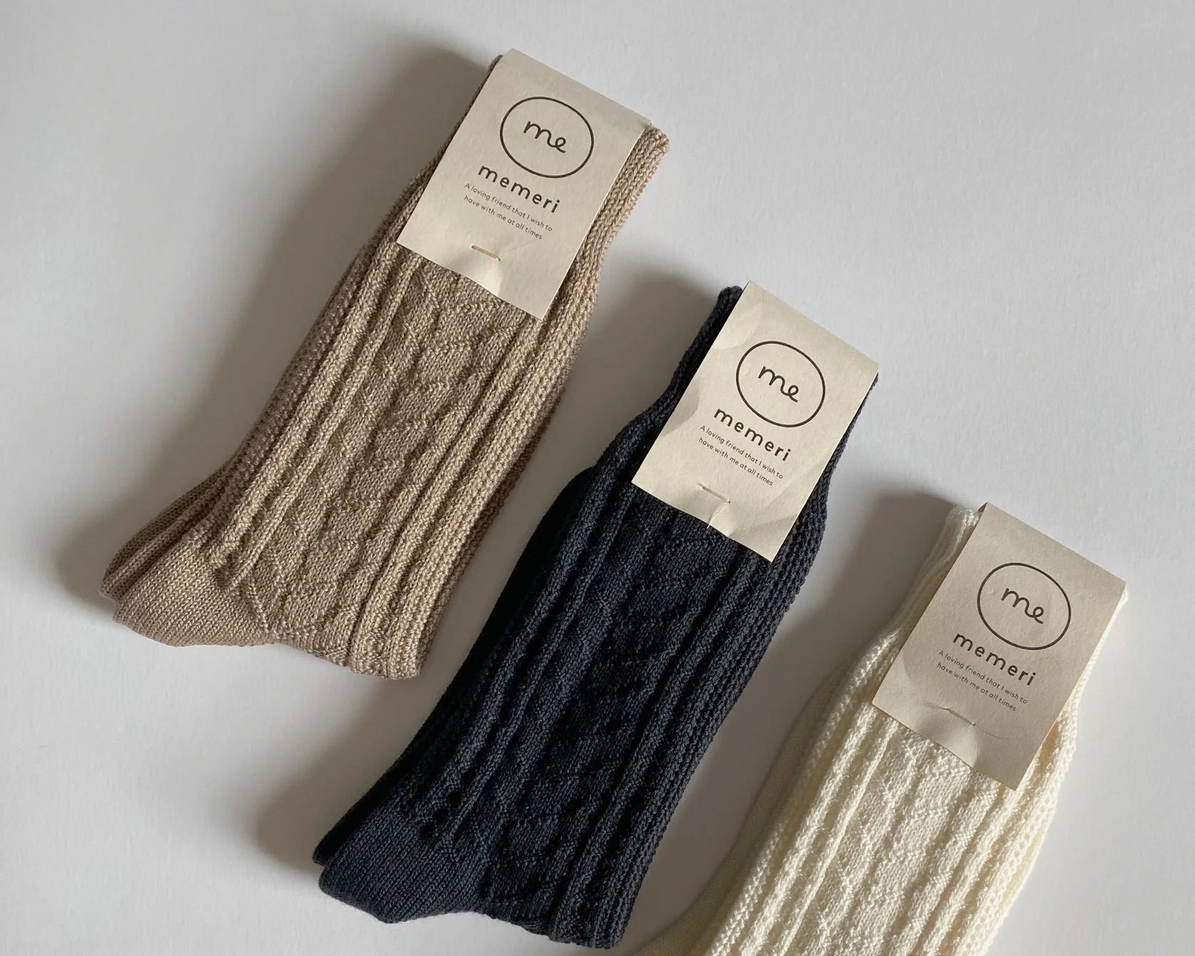 a line up of Memeri wool cotton cable knit socks on a plain background