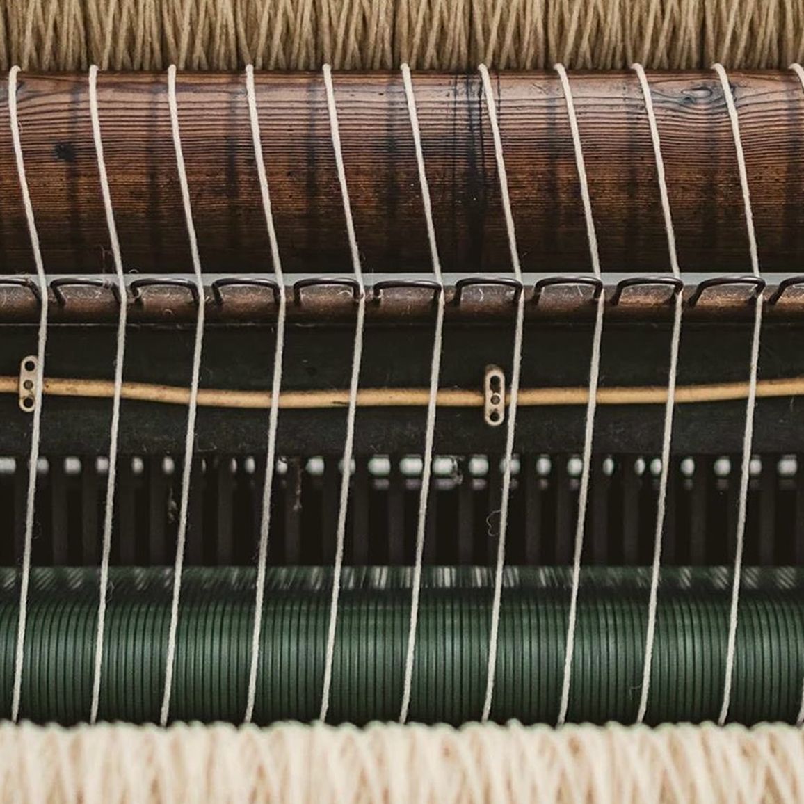 Close-up of a Burel merino wool blanket being woven on a historic loom in Portugal, showcasing traditional textile craftsmanship and hand-finishing, available at Handcrafted Modern.