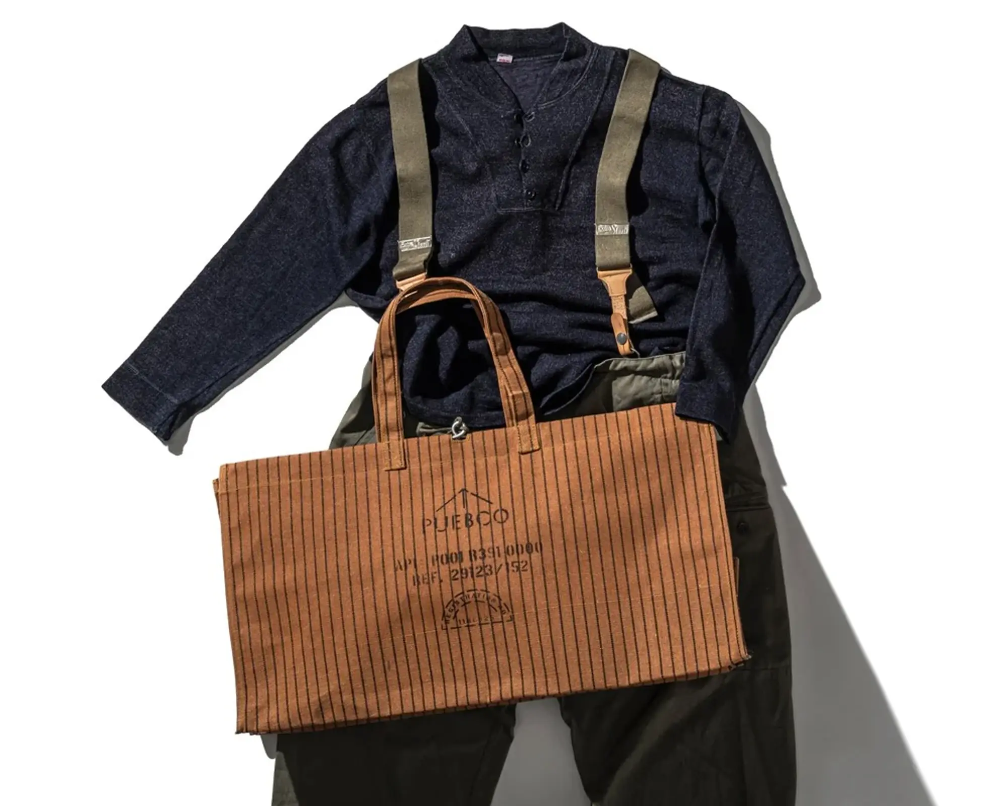 The Puebco waxed canvas bag in the large size onto of a flatlay of an outfit