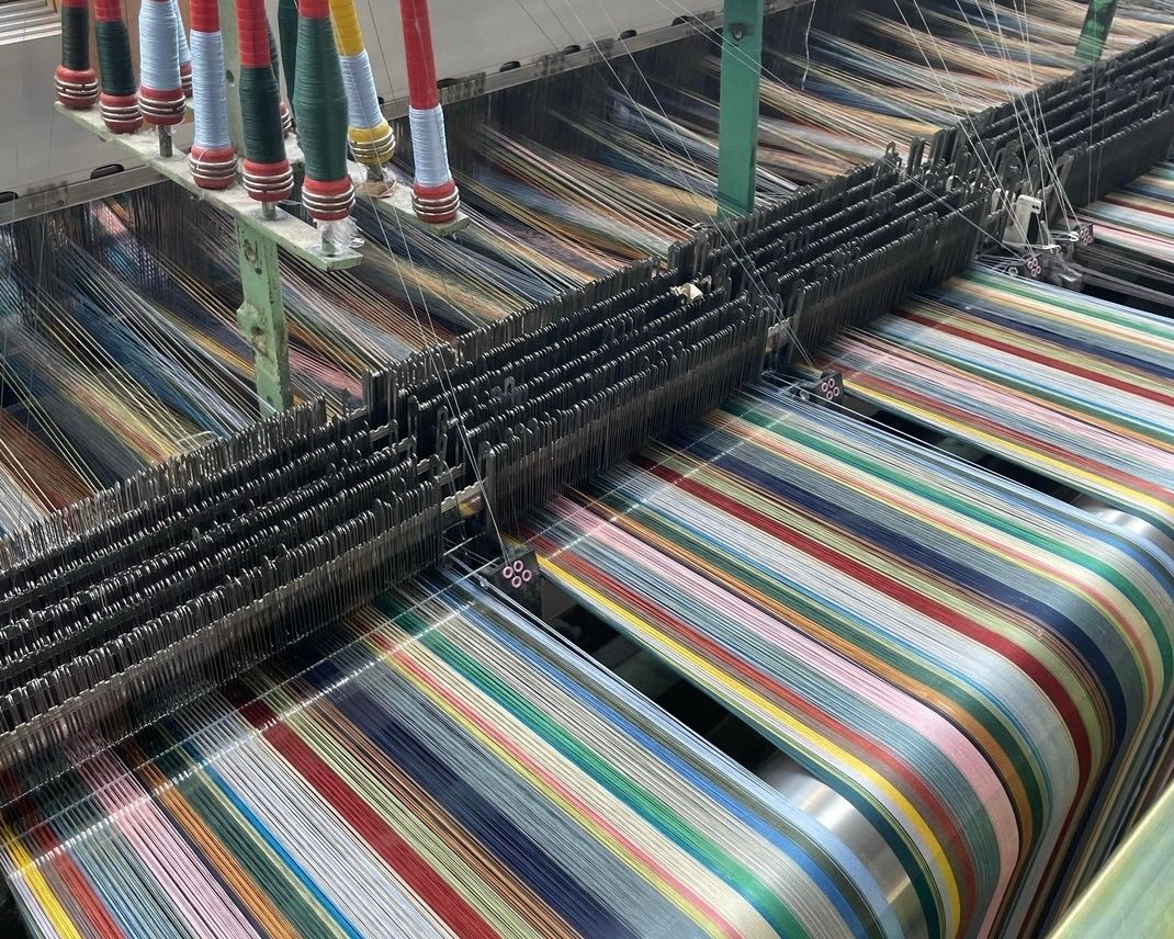 Wallace Sewell merino wool scarves on the loom, showing colourful woven patterns and intricate textile construction.