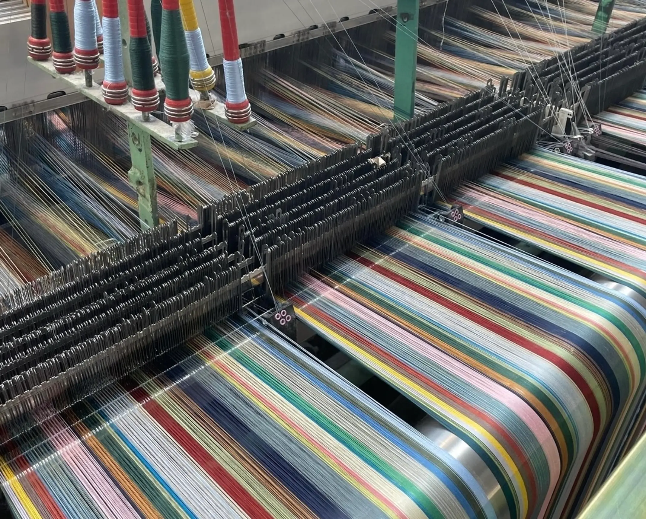 Wallace Sewell merino wool scarves on the loom, showing colourful woven patterns and intricate textile construction.