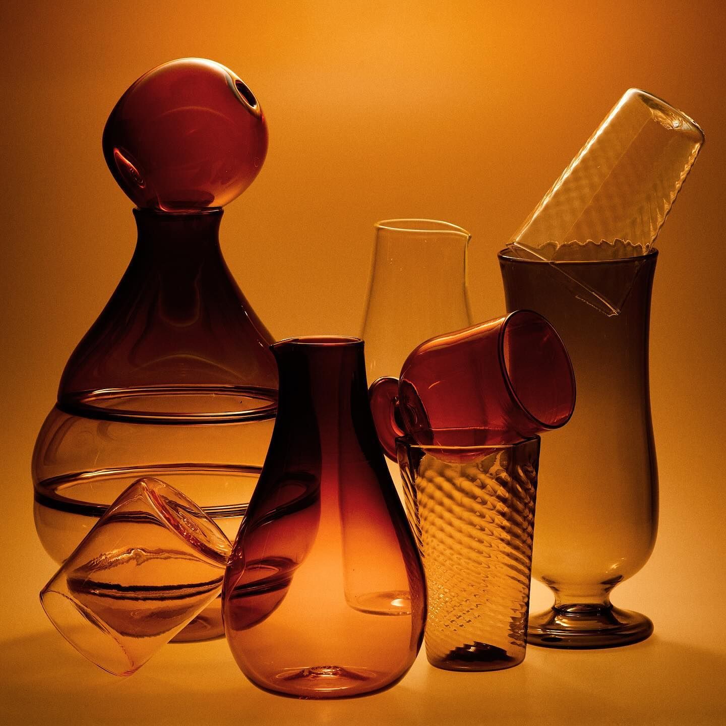 Glass vessels stacked with a burnt orange background 