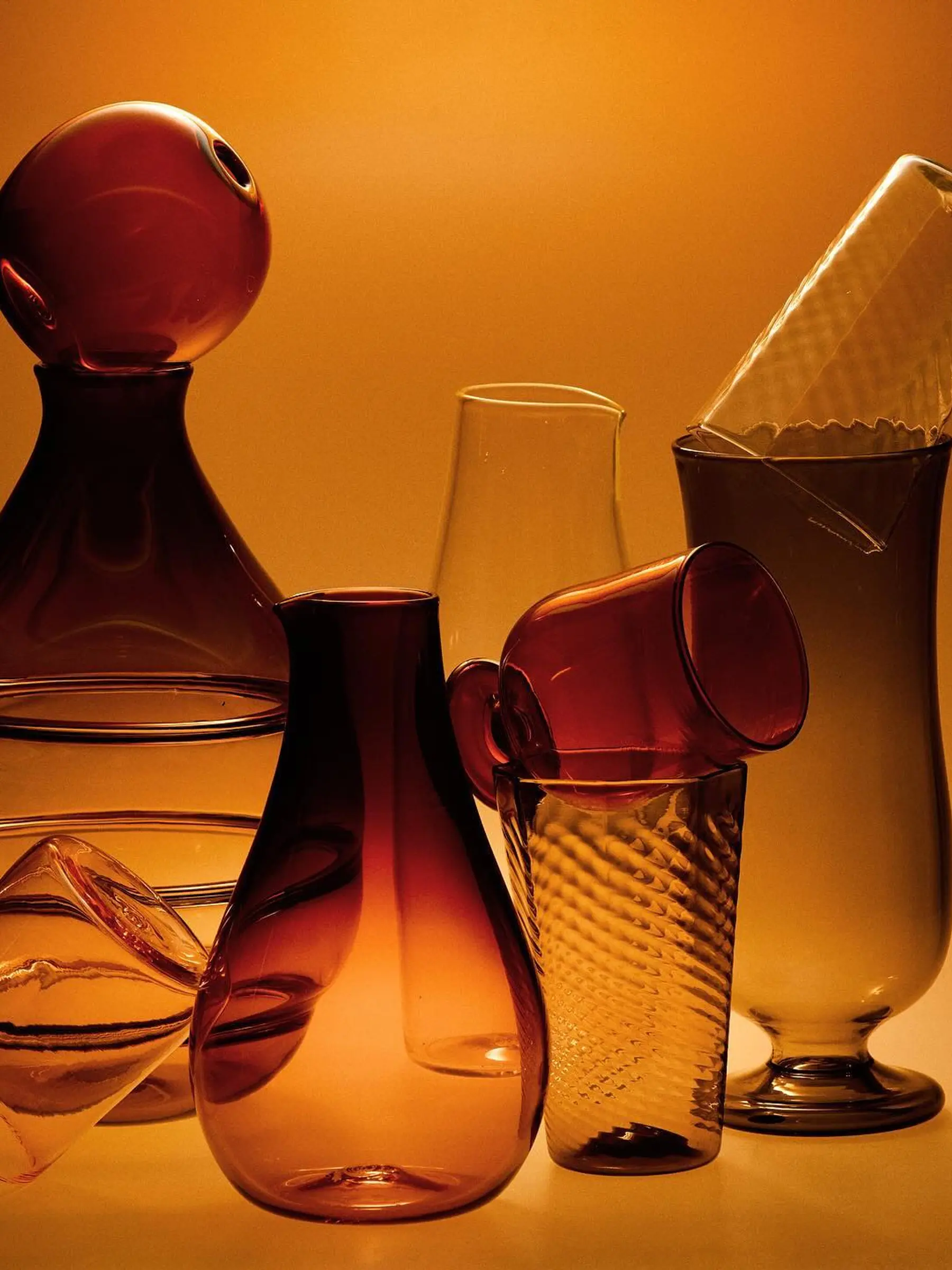 Glass vessels stacked with a burnt orange background
