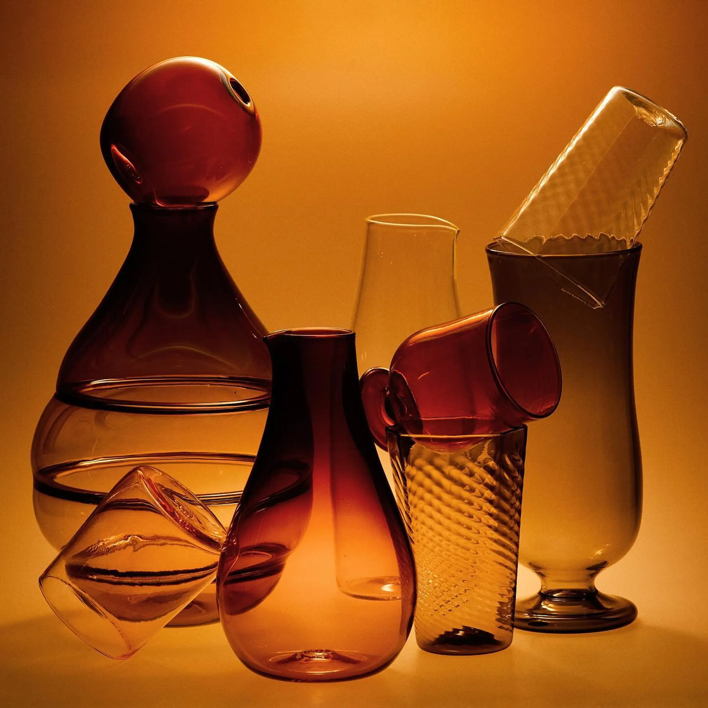 Glass vessels stacked with a burnt orange background