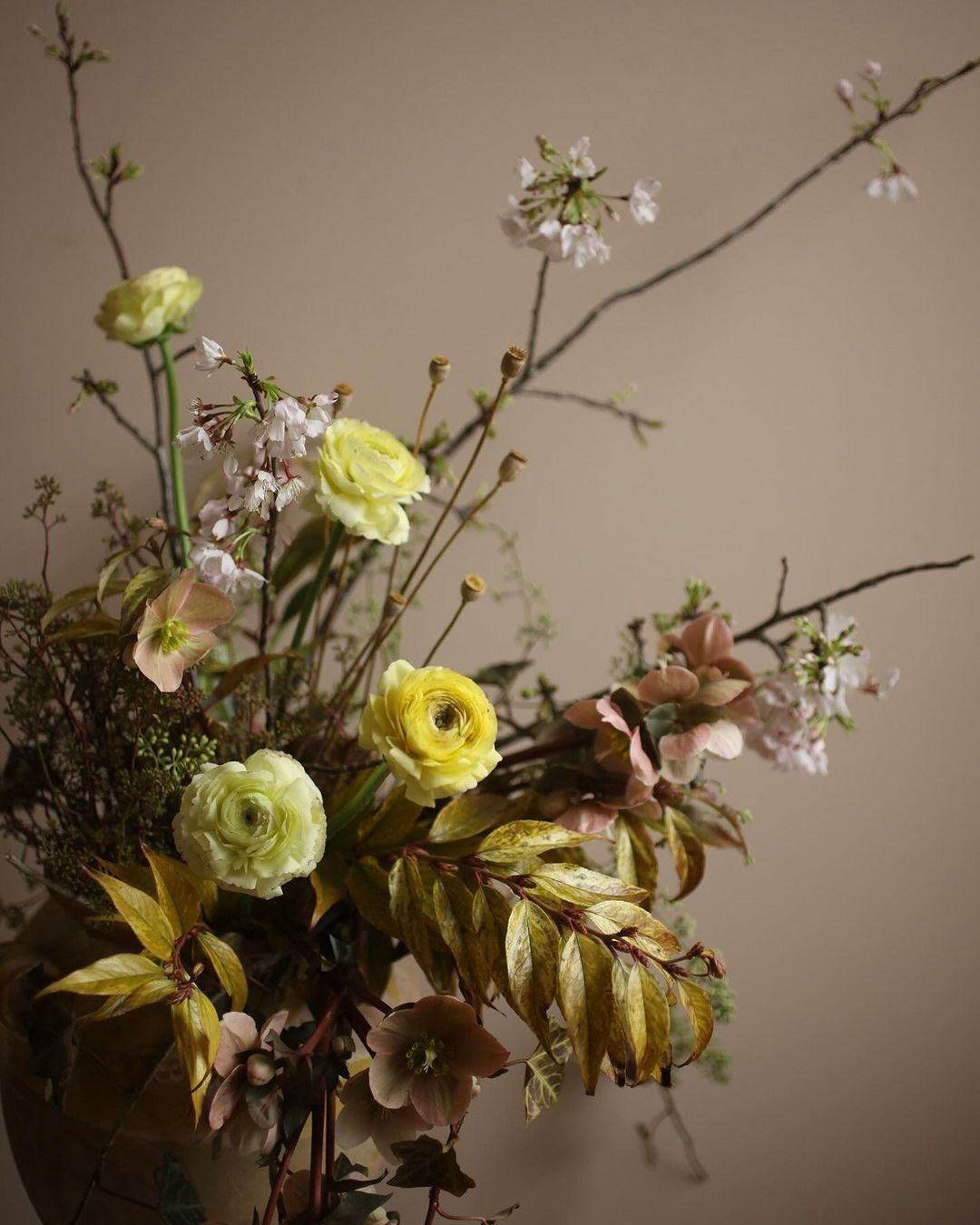 A floral arrangement photo in yellow tones on a brown wall