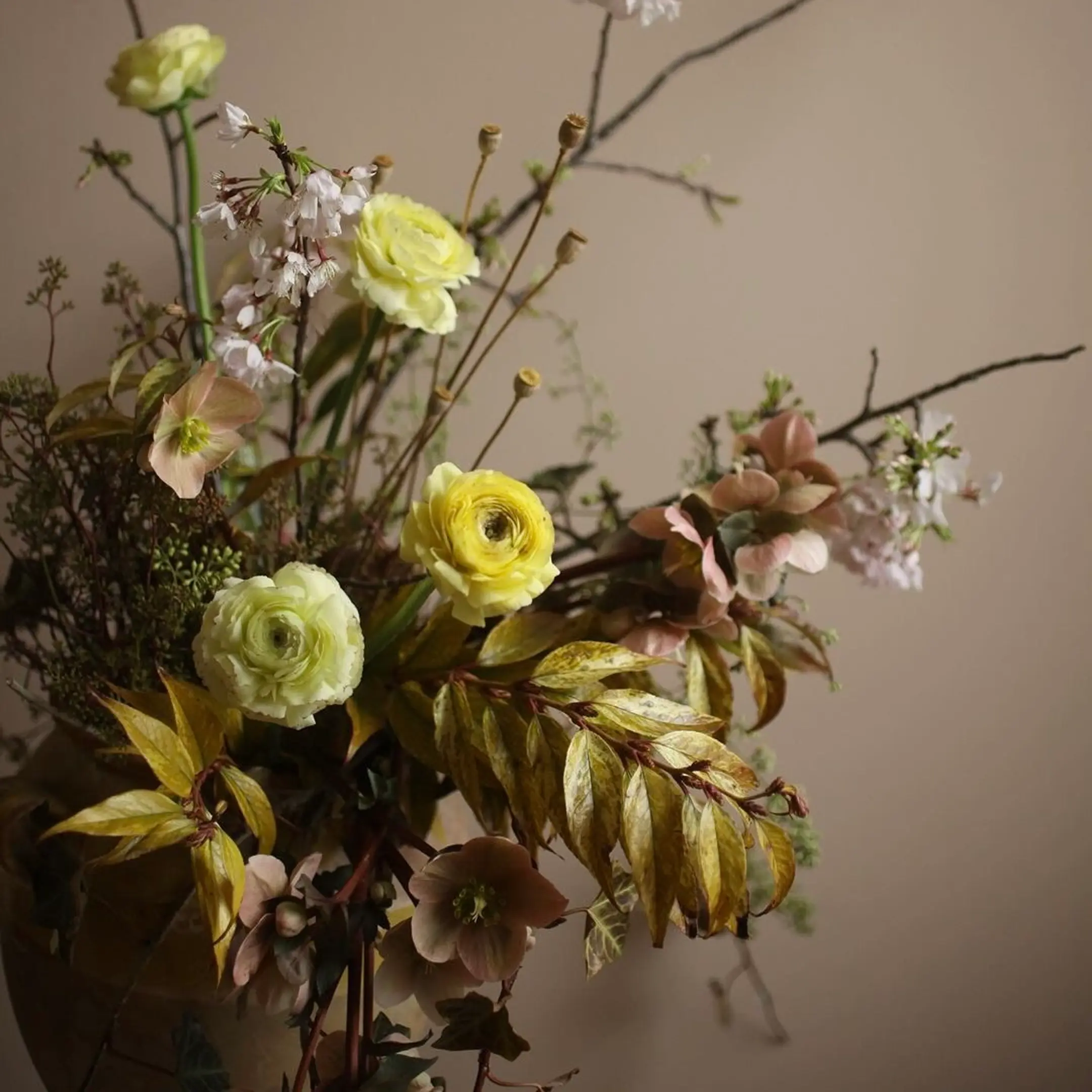 A floral arrangement photo in yellow tones on a brown wall