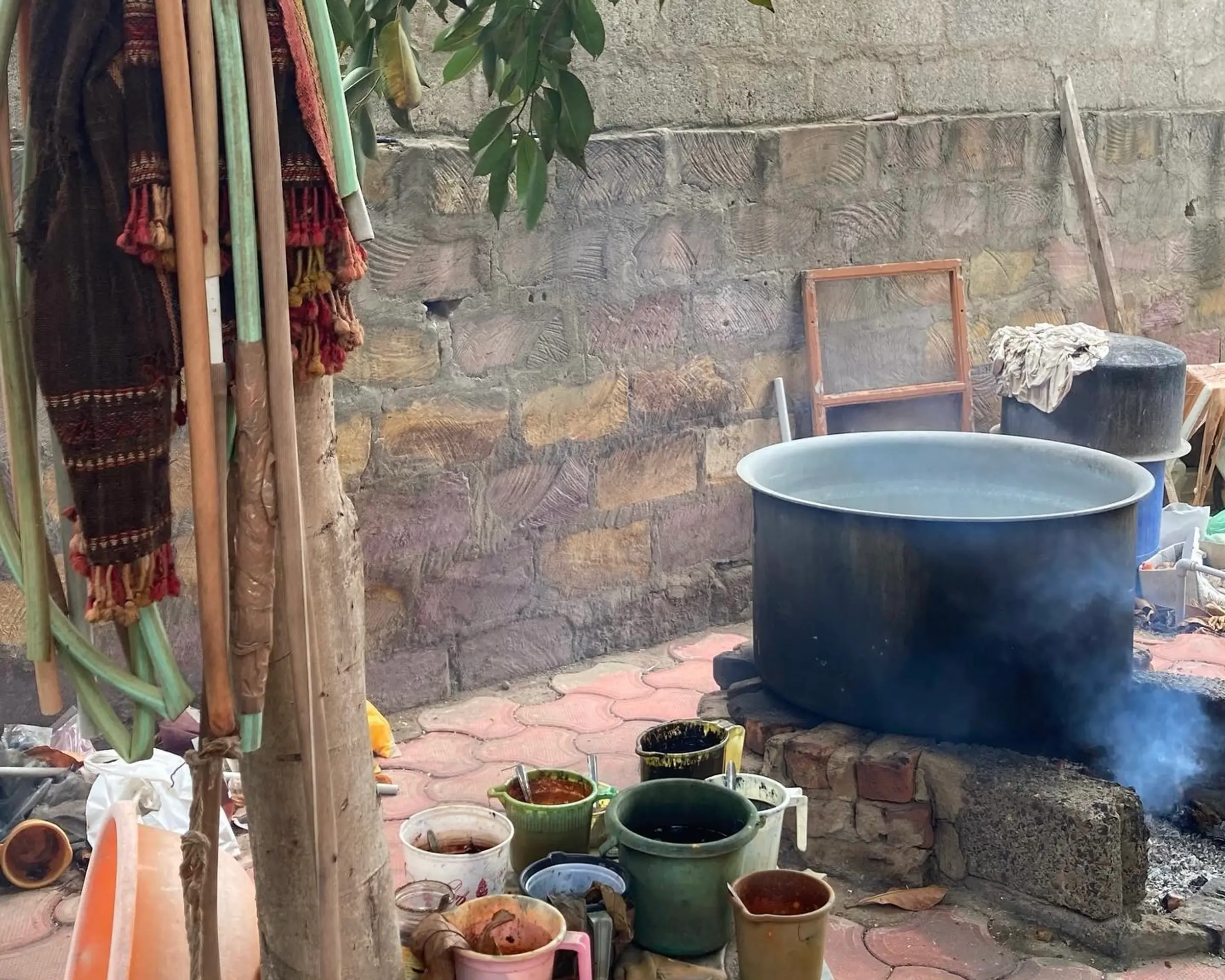 A photo of an outdoor setting in India of a dyepot and various natural colour mixes in pourers nearby