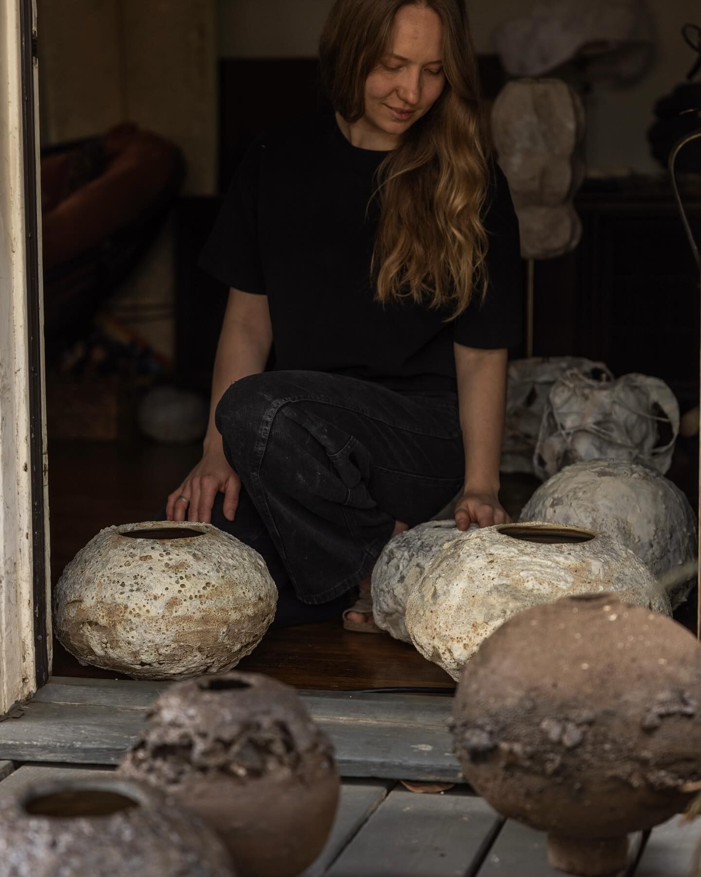 An image of Maria Loram with a collection of her ceramic vases in organic forms