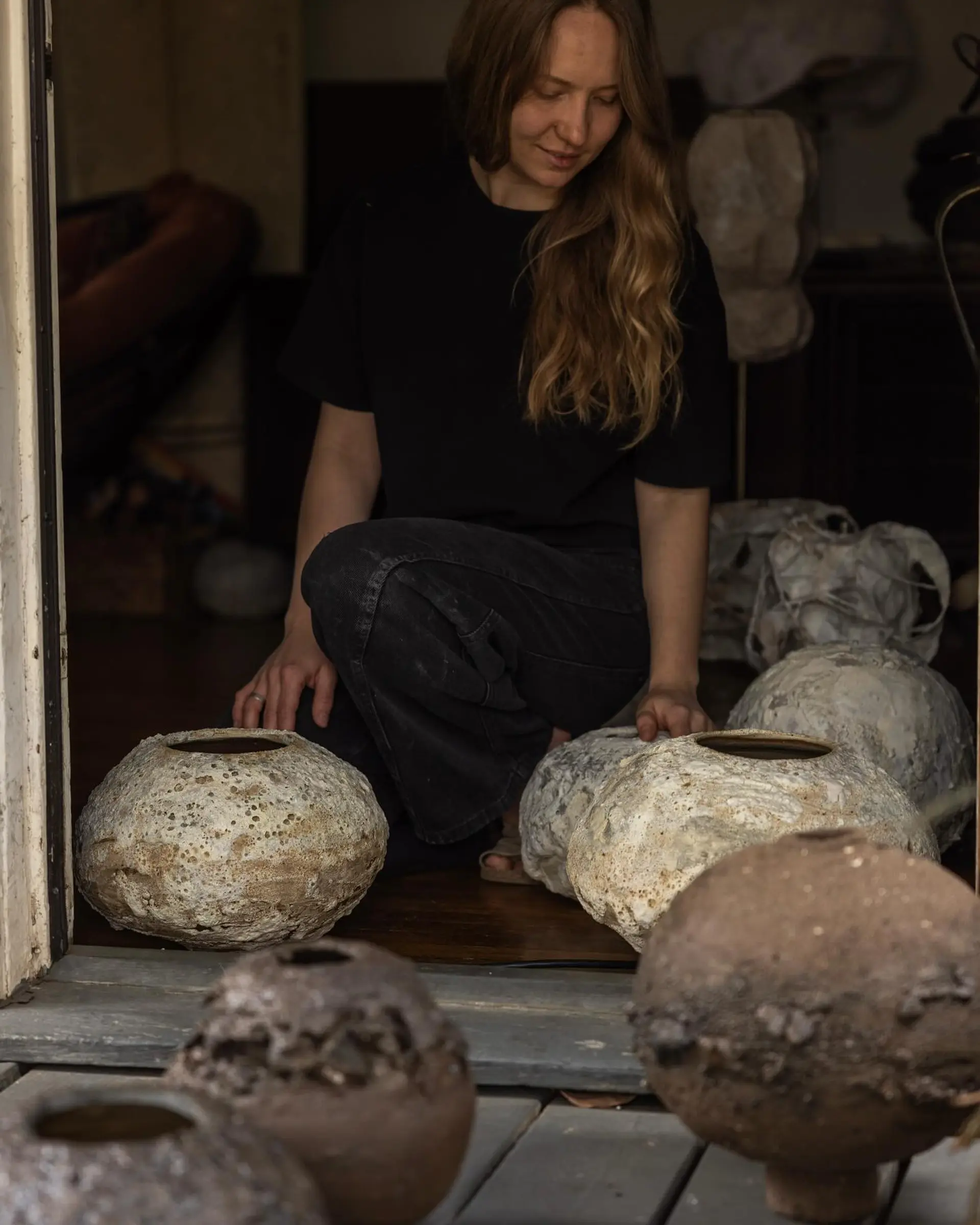 An image of Maria Loram with a collection of her ceramic vases in organic forms