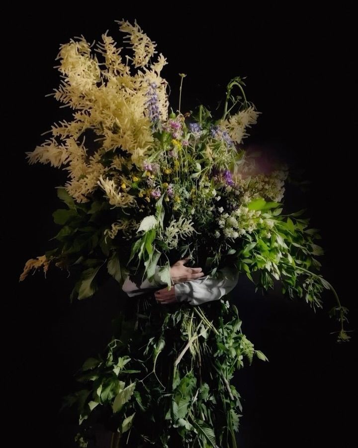 a man holding a bunch of flowers as tall as himself