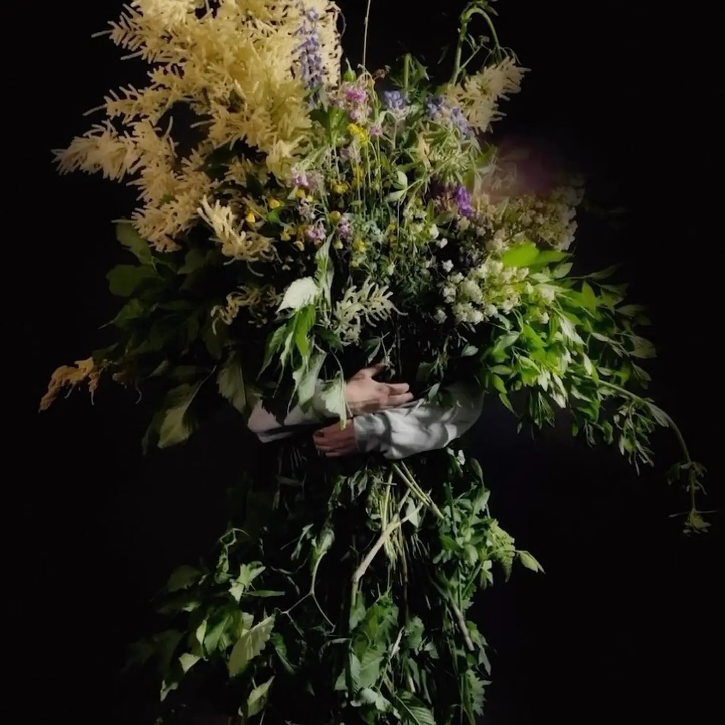 a man holding a bunch of flowers as tall as himself