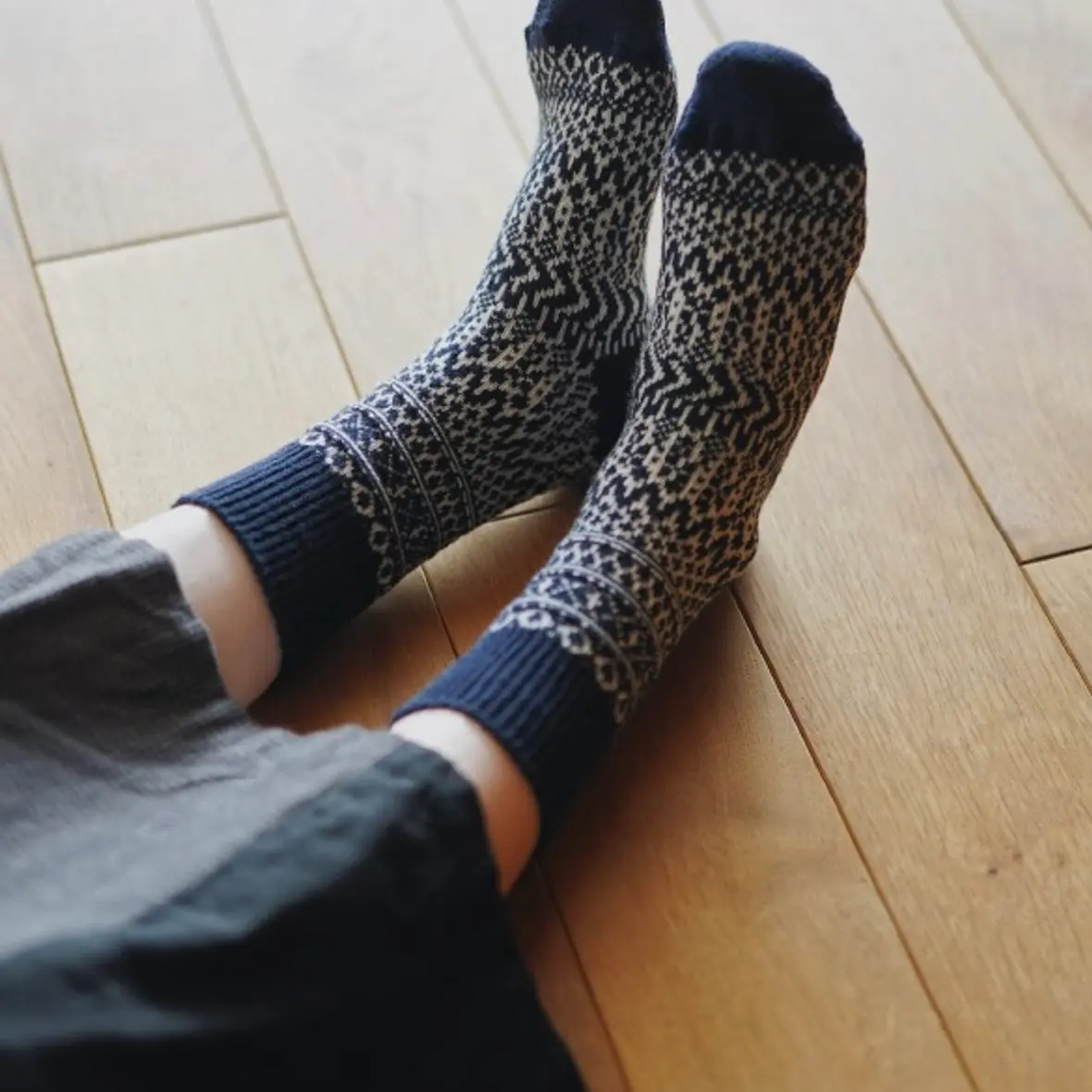 warm woolen socks worn on feet laying on a wood floor