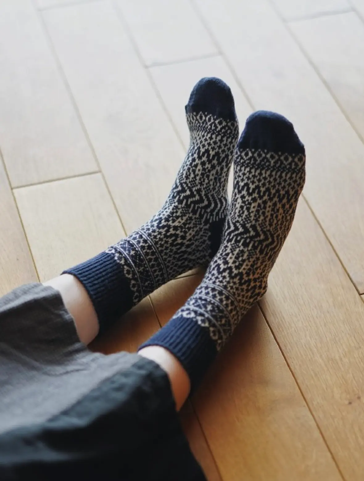 warm woolen socks worn on feet laying on a wood floor