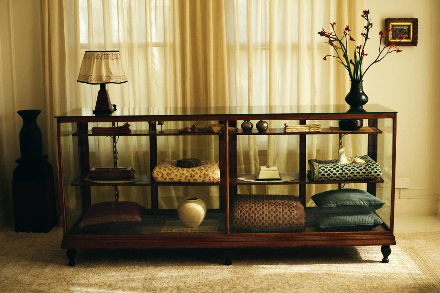 Studio Ford showroom in Los Angeles featuring antique designer furniture and shelves with folded textiles. Hand block printed and stitched quilts, throws and table linens.