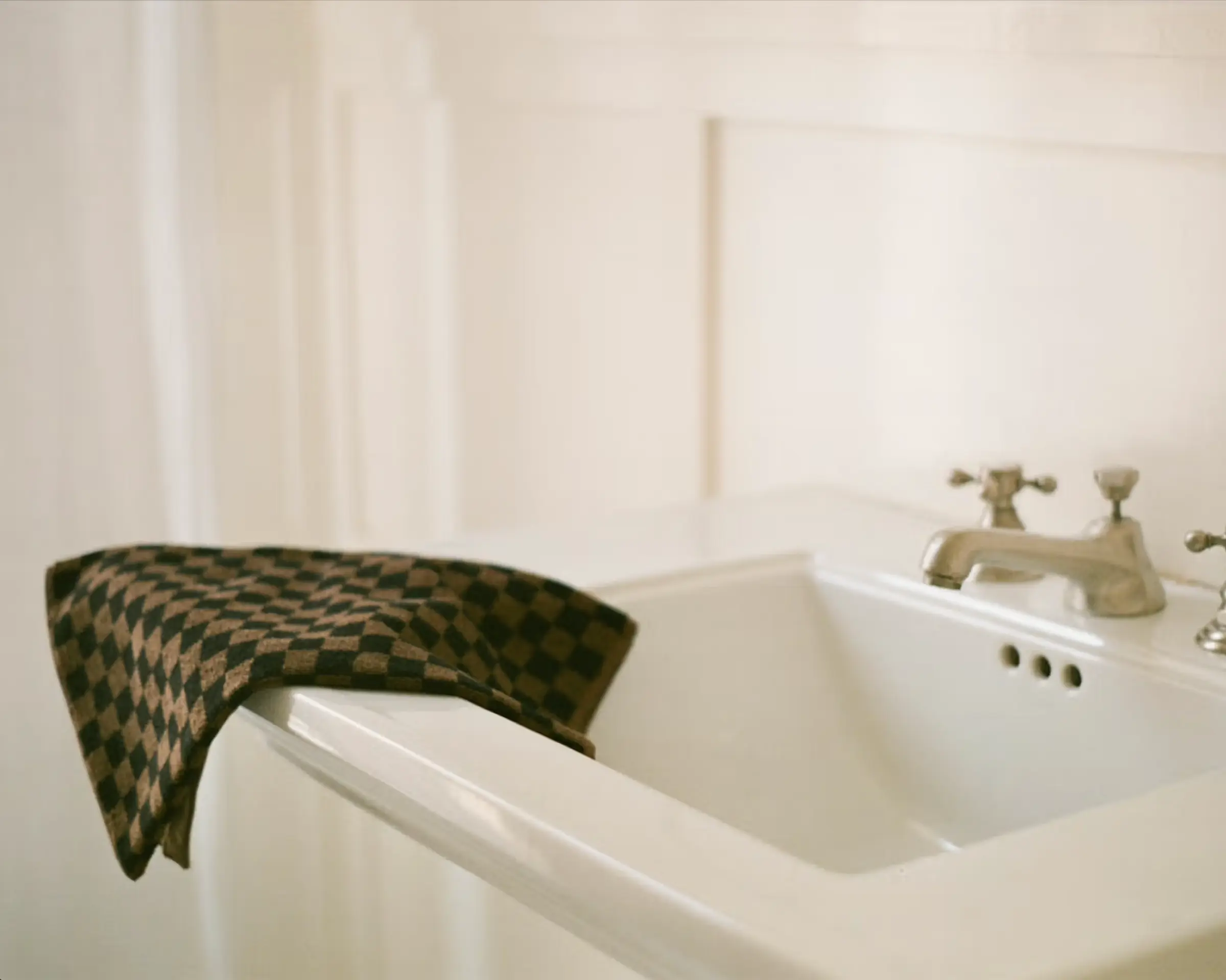Black and brown checkered hand towel hung over a white sink