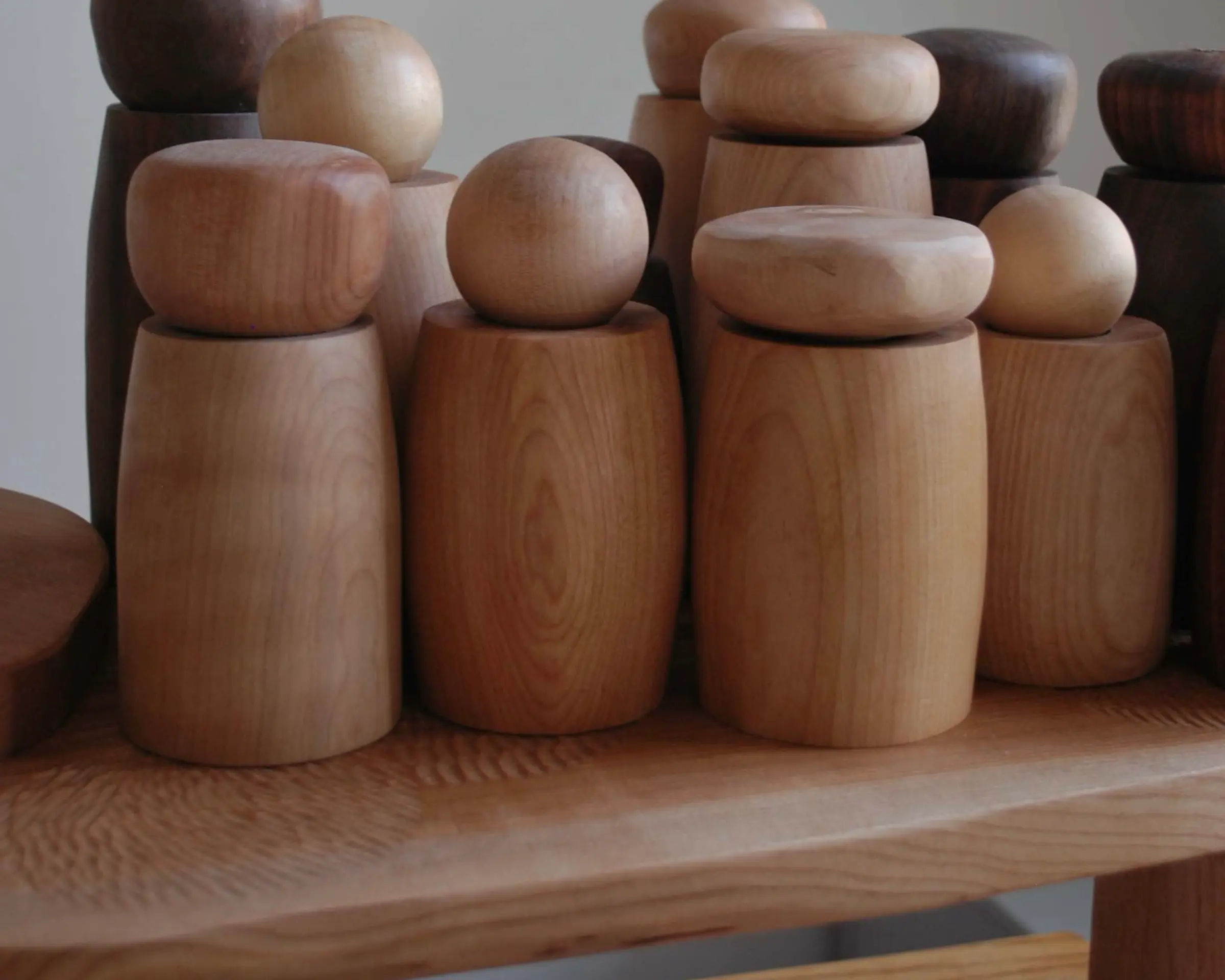 a collection of handmade wooden pepper mills on a table top