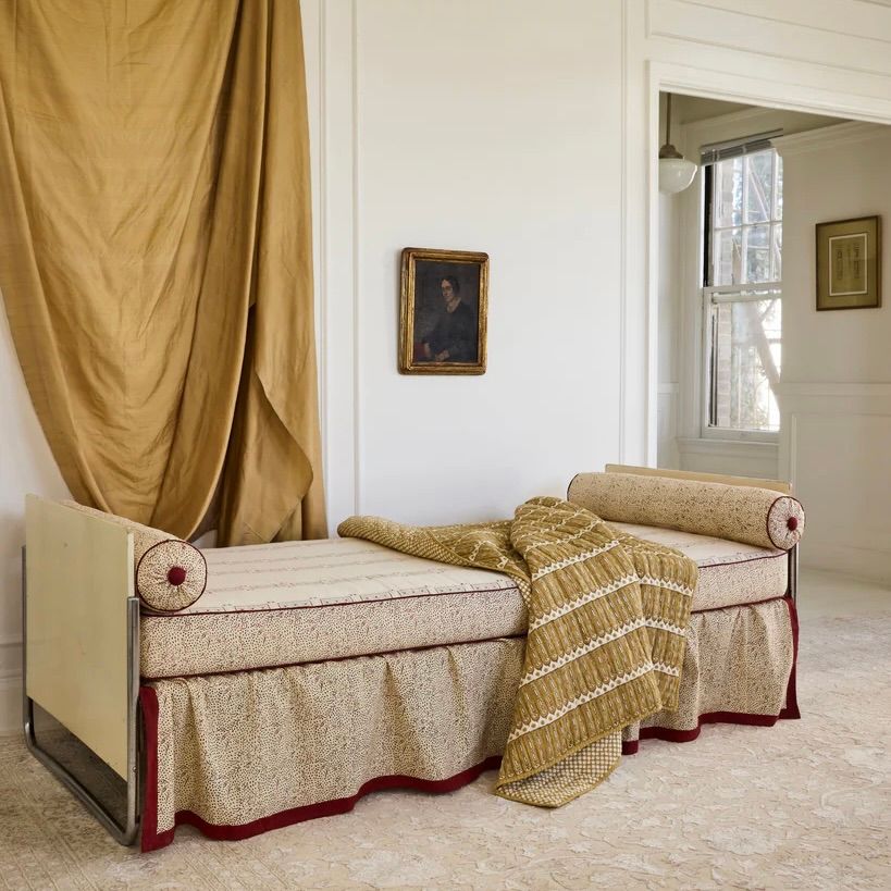 a room with draped curtain fabric and an antique couch with a studio ford aurea throw over it 
