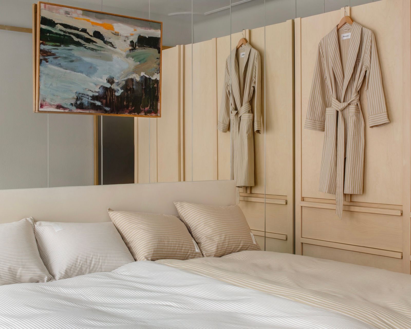 Wall Street Oxford Pima Cotton Duvet Covers in stripe medium beige, paired king singles on a super kind bed in a modern bedroom with a built in wardrobe, robe hanging and abstract painting being the bed on a mirrored wall. 