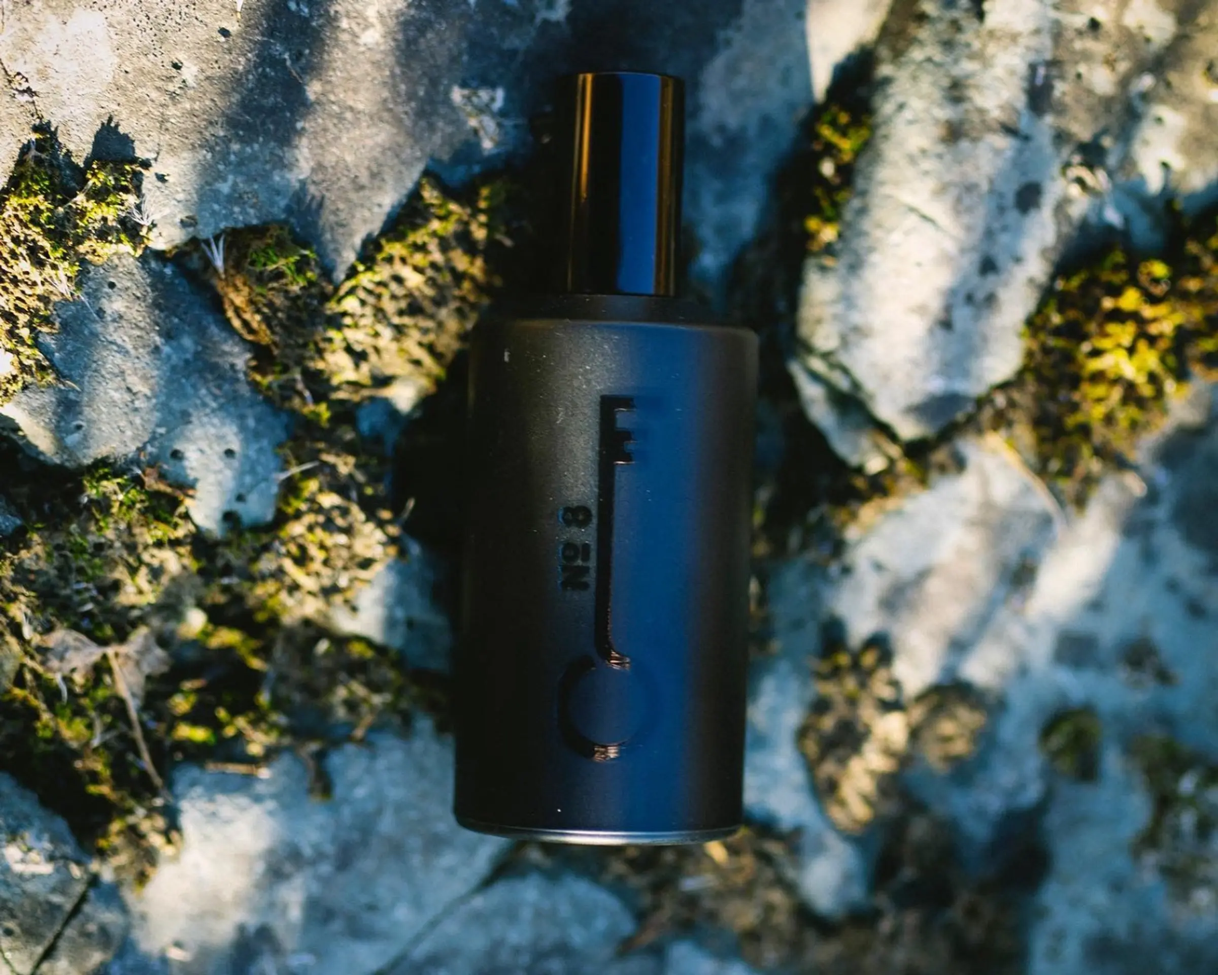 bottle of fischersund fragrance ontop of rocks and moss