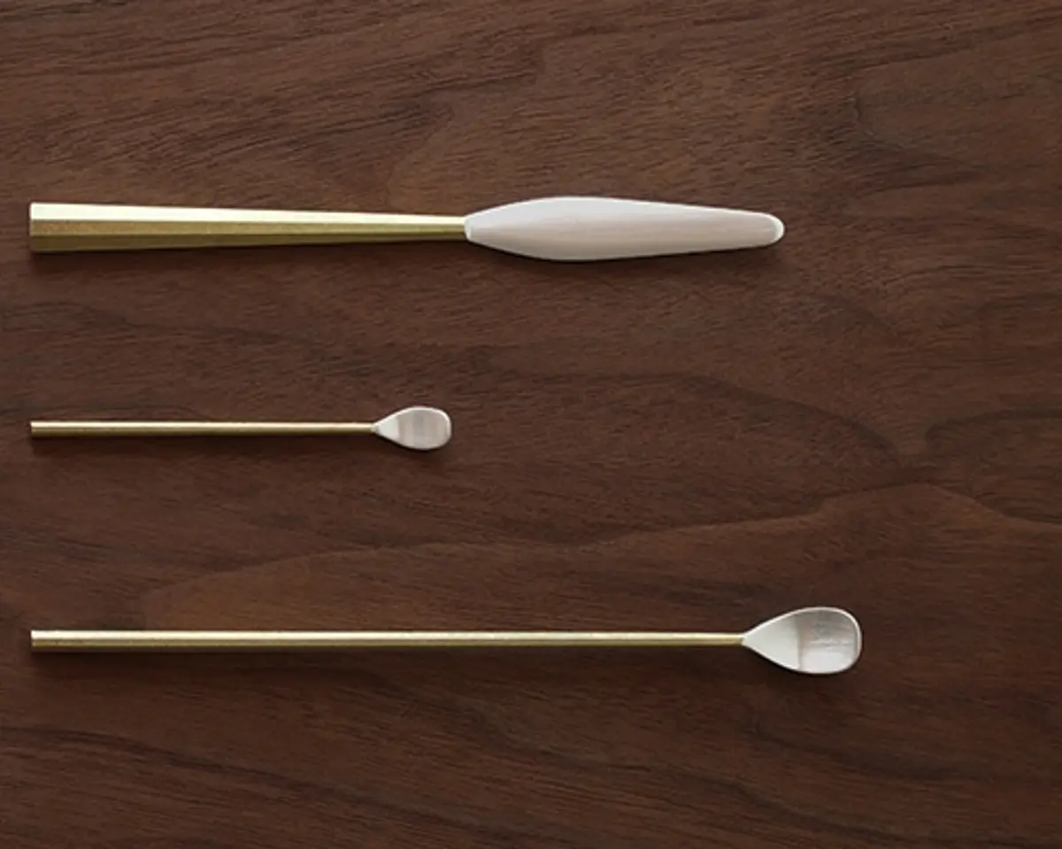 silver and brass handmade utensils on a wooden surface